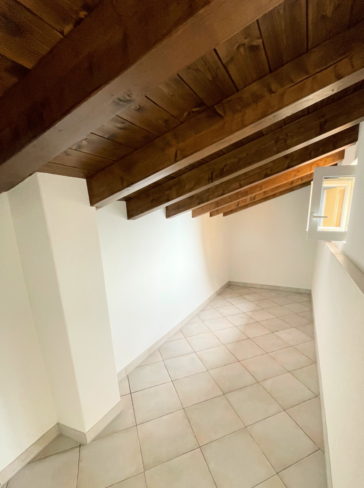 Dachgeschoss-Flur mit Holzdecke und Fliesenboden
