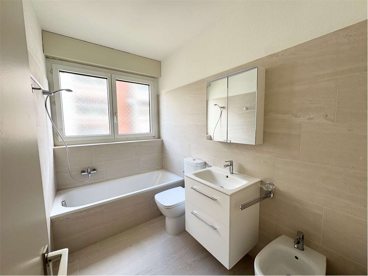 Modernes Badezimmer mit Badewanne, Waschtisch und Fenster