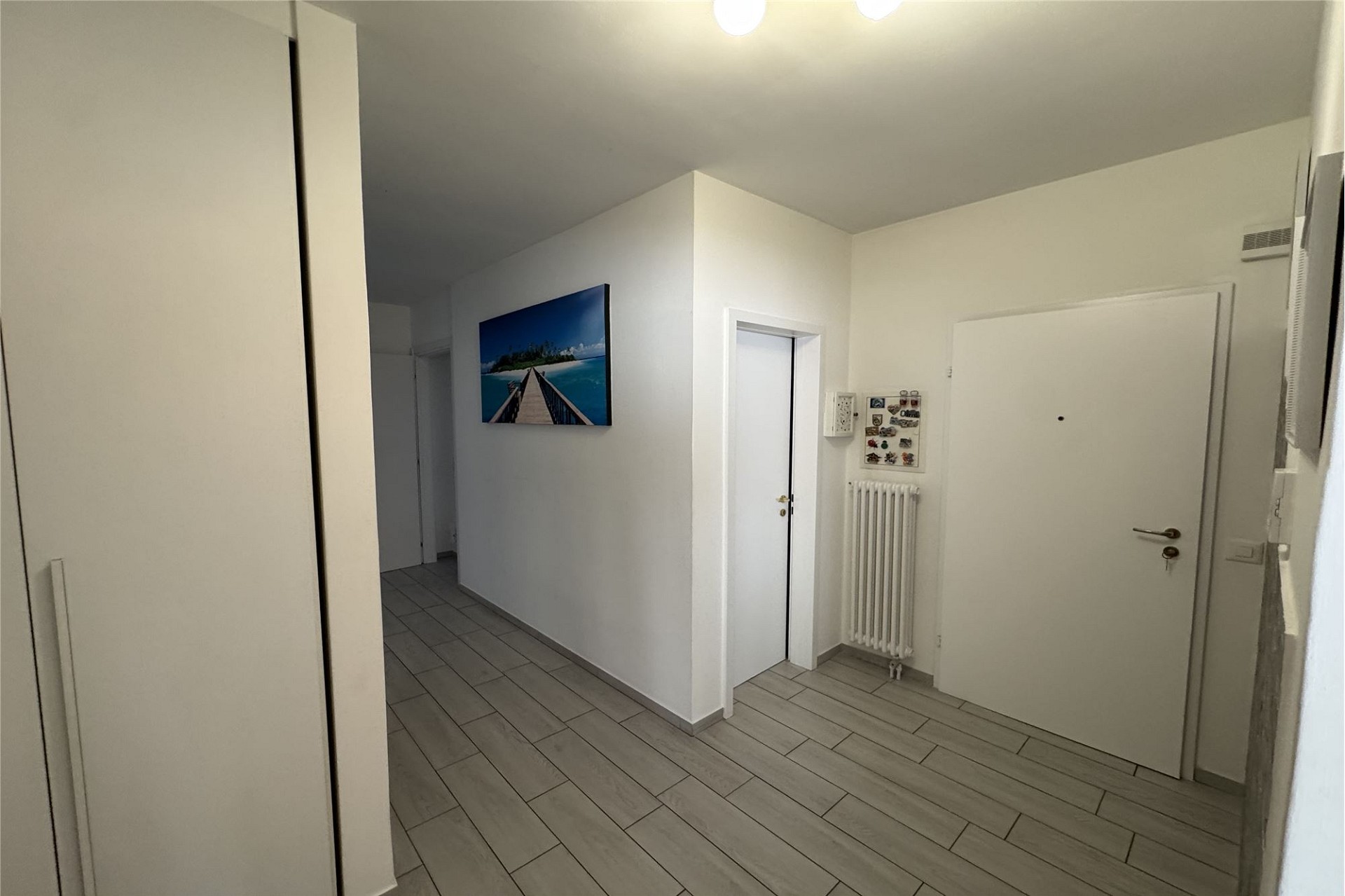 Heller Flur mit weißen Türen und grauem Boden