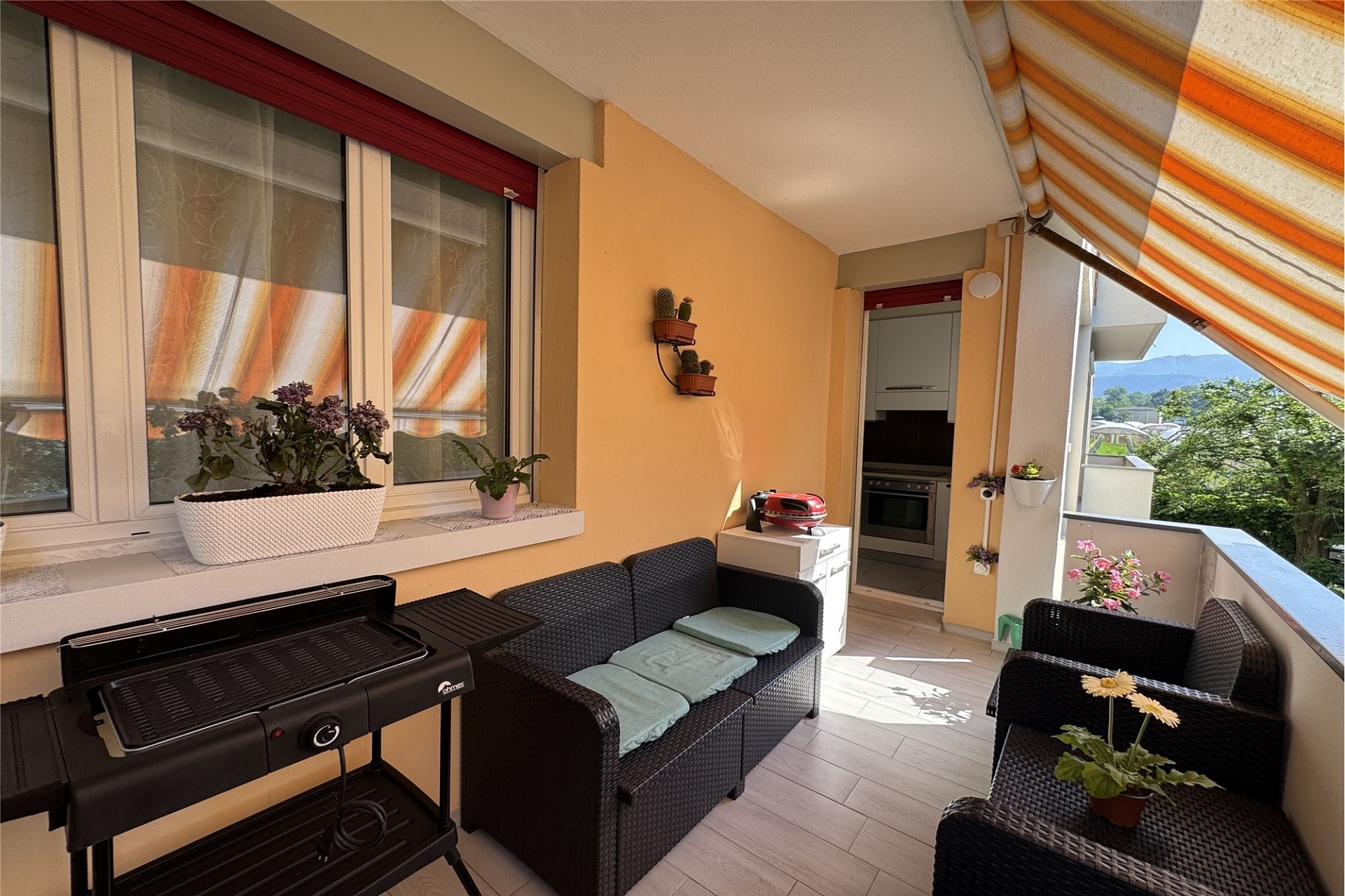 Überdachter Balkon mit Sitzgruppe und Grill