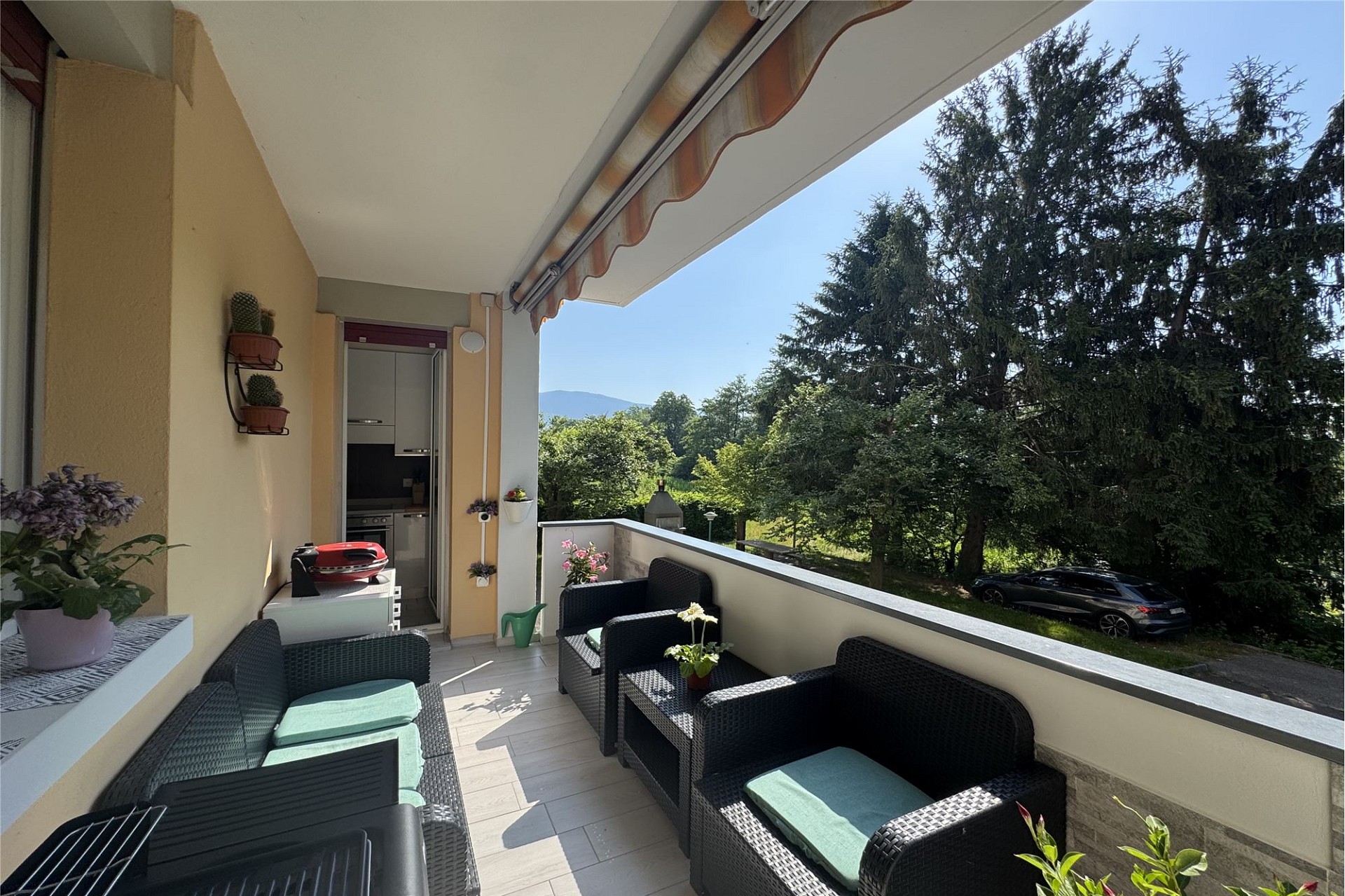 Überdachter Balkon mit Sitzgruppe und Grünblick