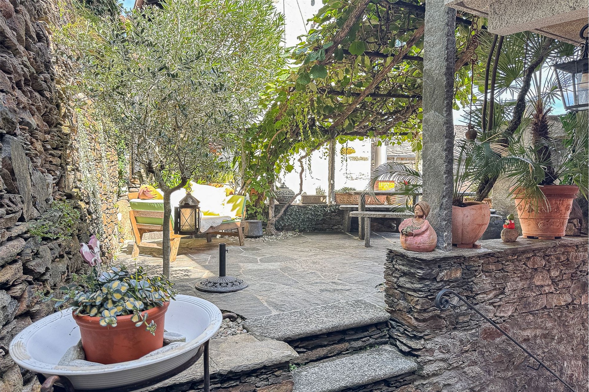 Mediterrane Garten-Terrasse mit Steinmauer und Pergola