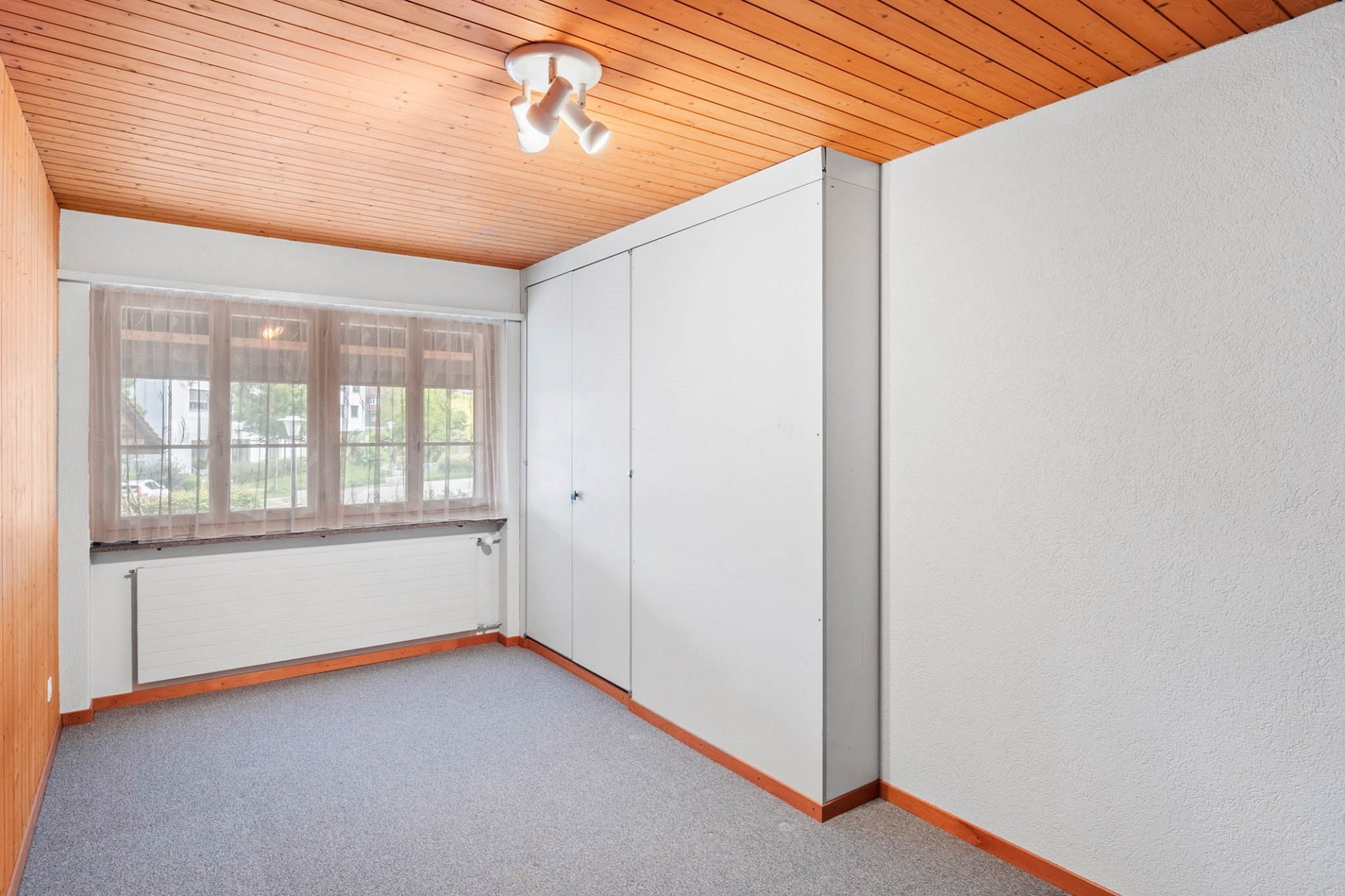 Leeres Zimmer mit Holzdecke und Einbauschrank
