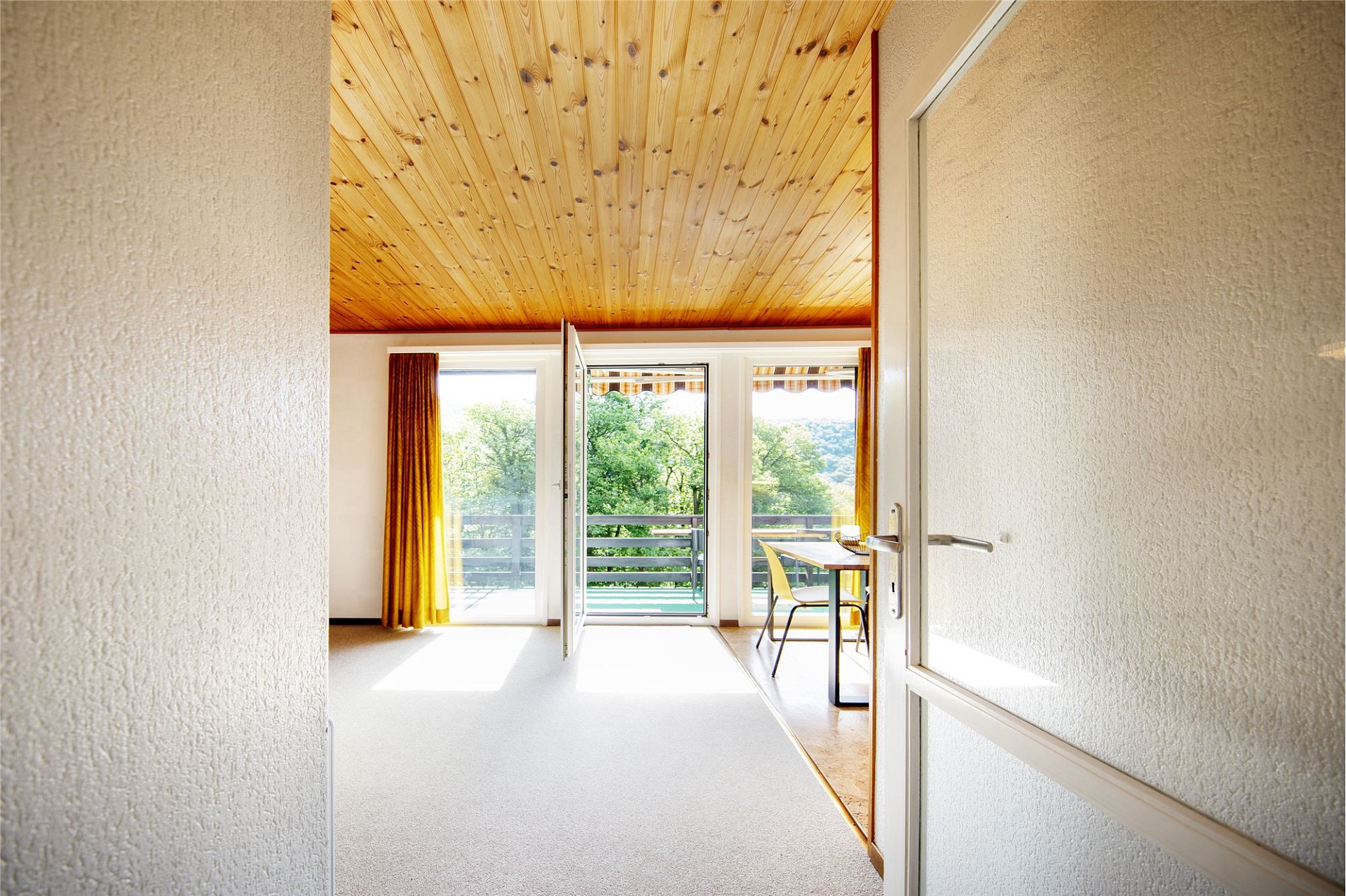Heller Raum mit Balkonblick und Holzbalkendecke