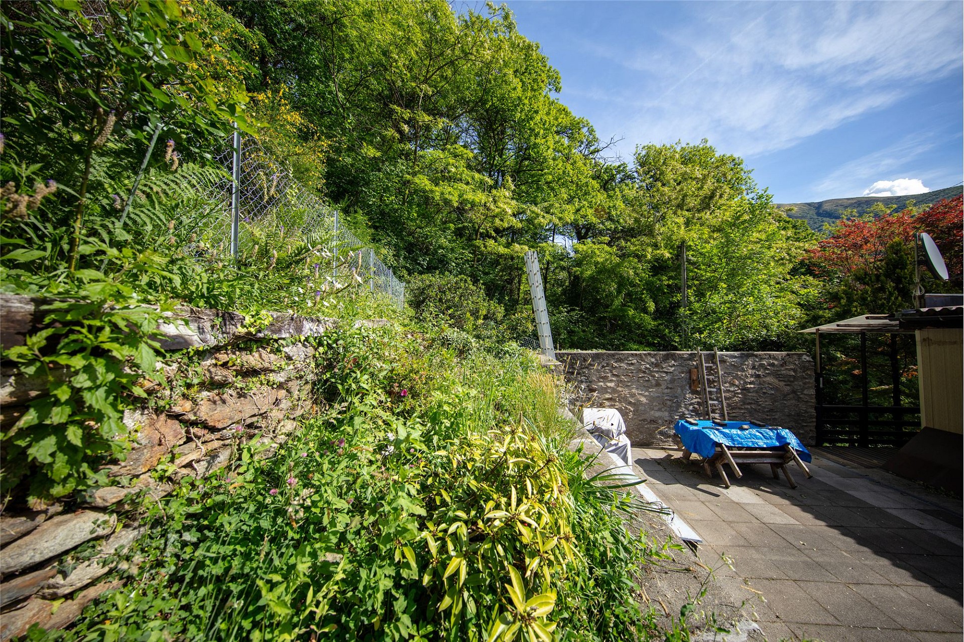 Terrasse mit Natursteinmauer und üppigem Garten
