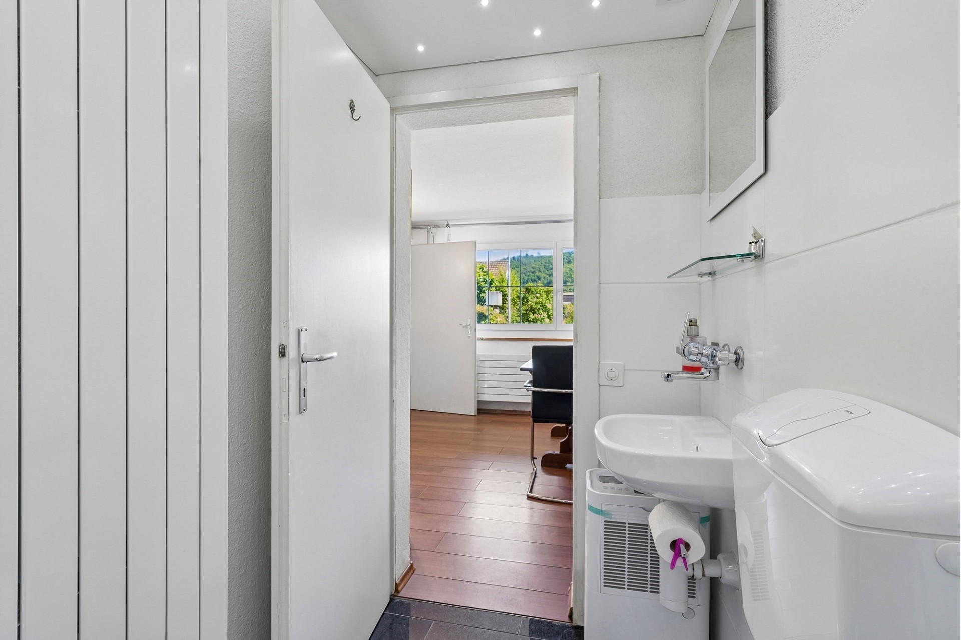 Helles Gäste-WC mit Blick in ein Arbeitszimmer