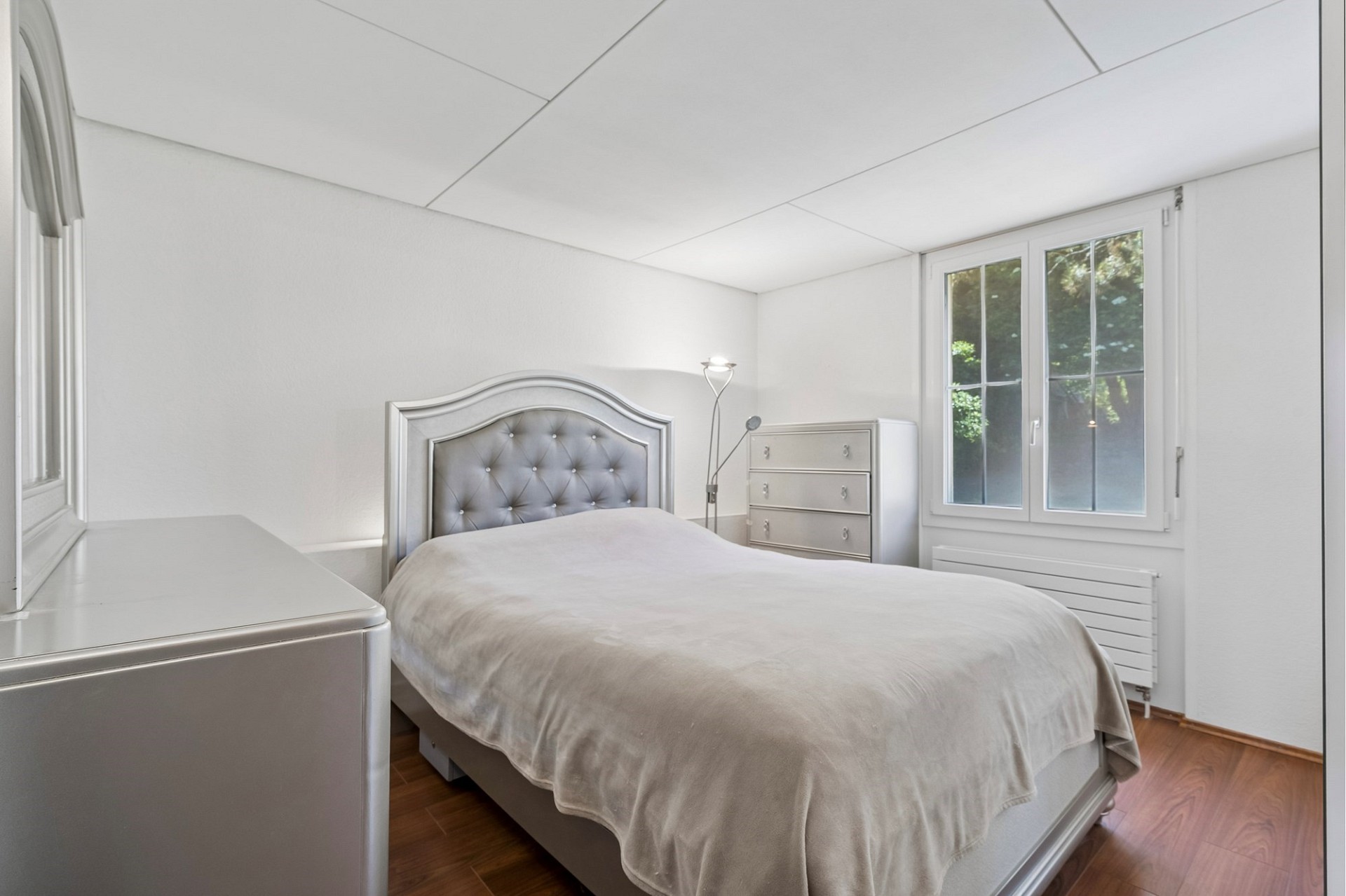 Helles Schlafzimmer mit grauem Polsterbett