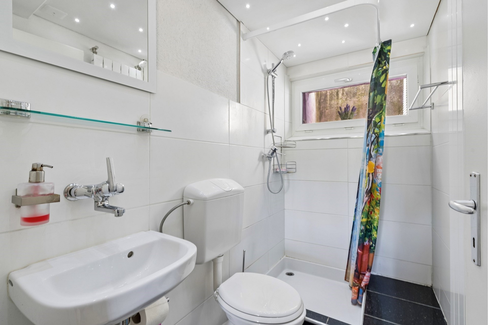 Kleines weißes Badezimmer mit Dusche und WC