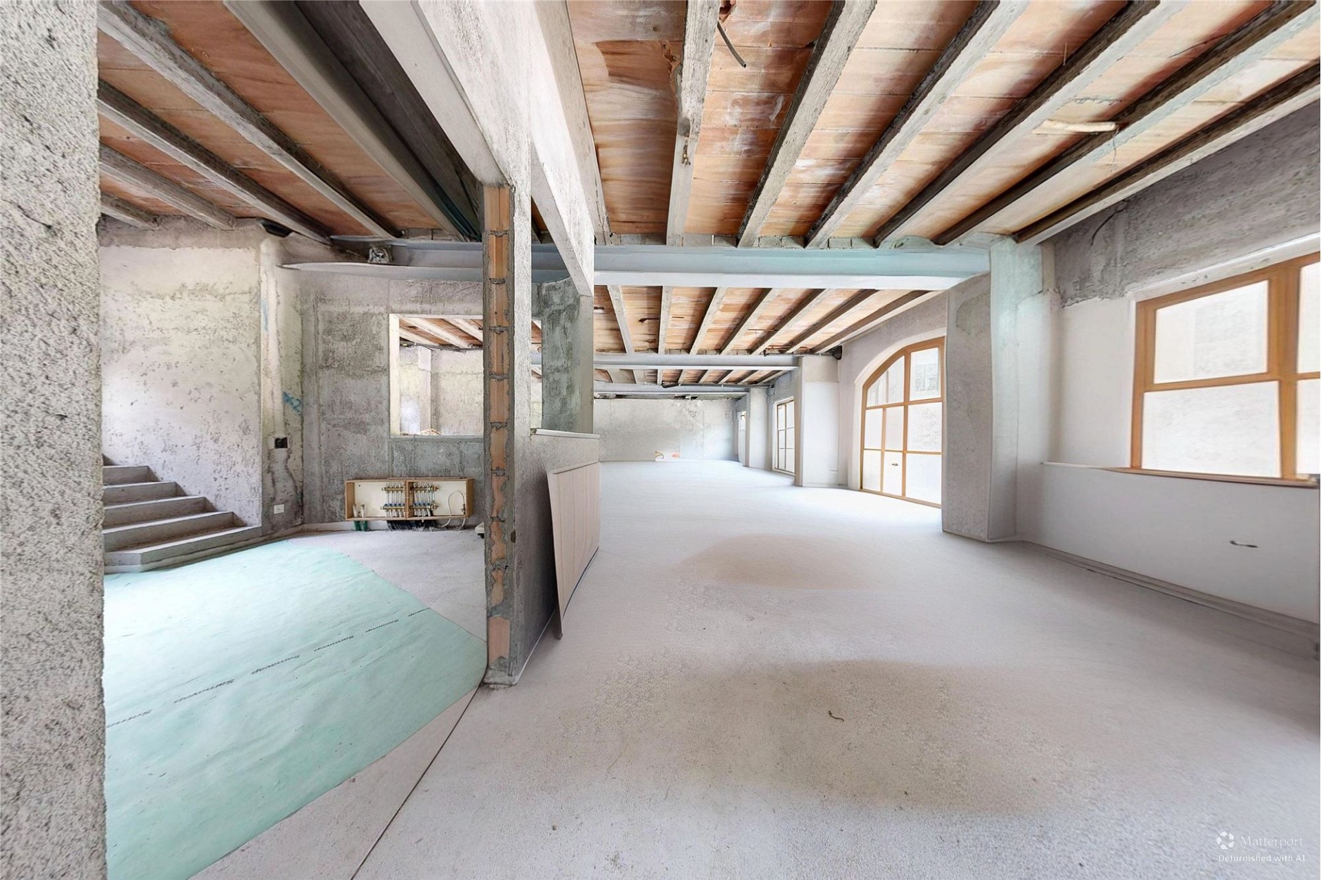 Unfertig ausgebauter Innenraum mit sichtbarer Rohbaukonstruktion