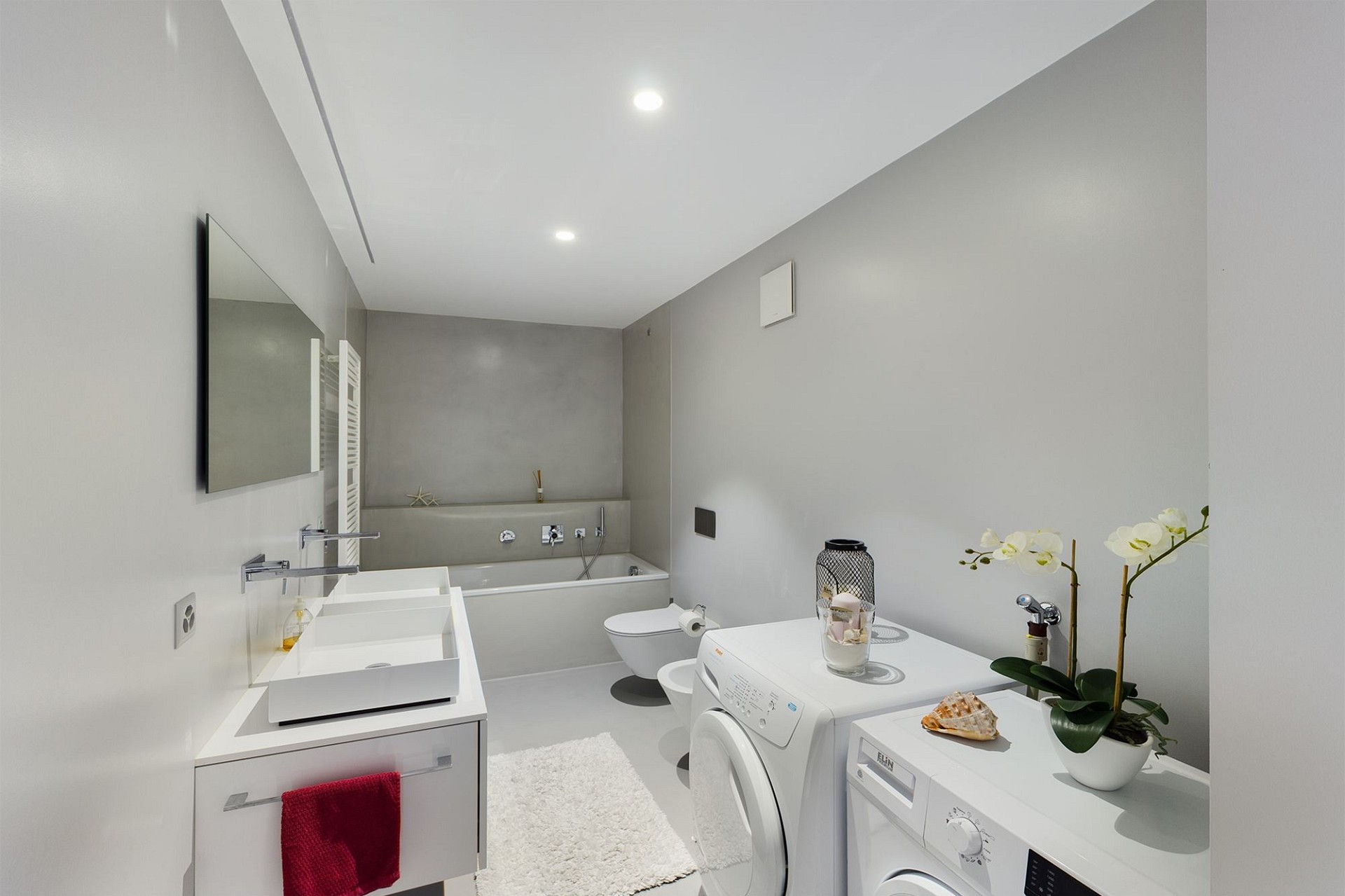 Heller Hauswirtschafts- bzw. Badezimmerraum mit Waschbecken, Badewanne und Waschmaschine