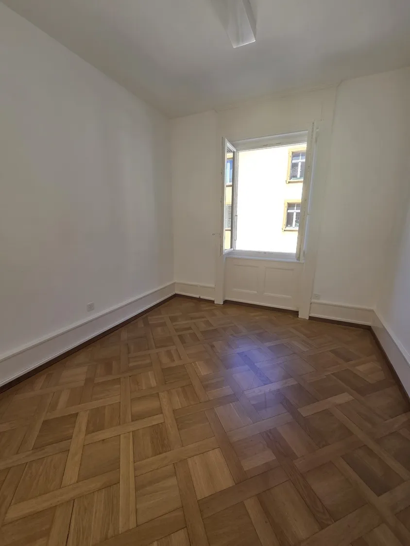Leerer Raum mit Fischgrätparkett und offenem Fenster
