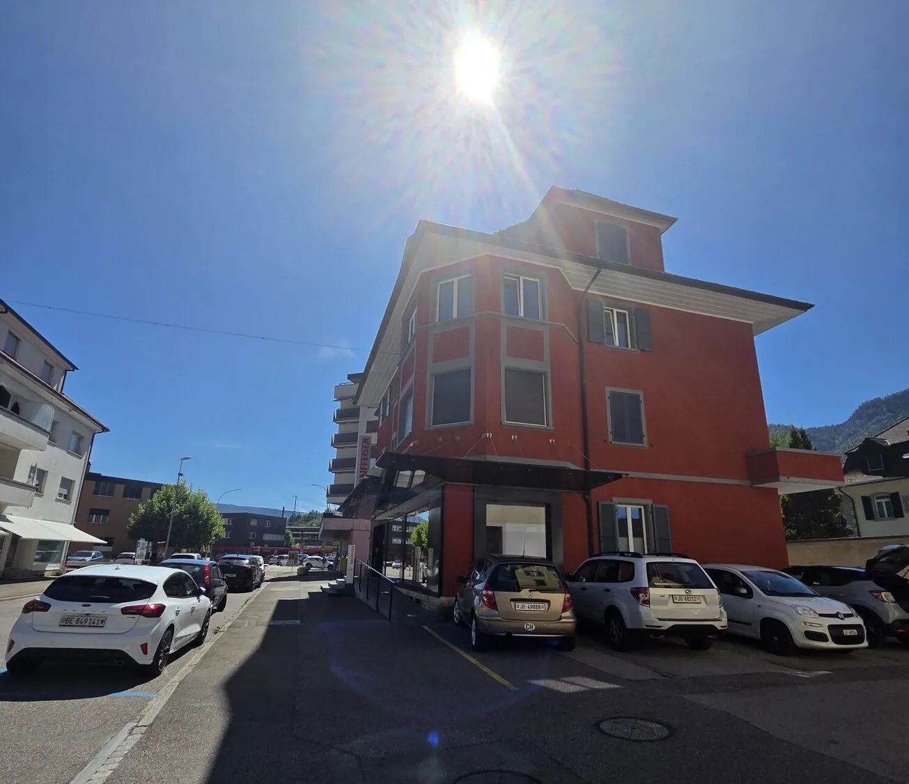 Straßenansicht eines mehrstöckigen Gebäudes bei direkter Sonne