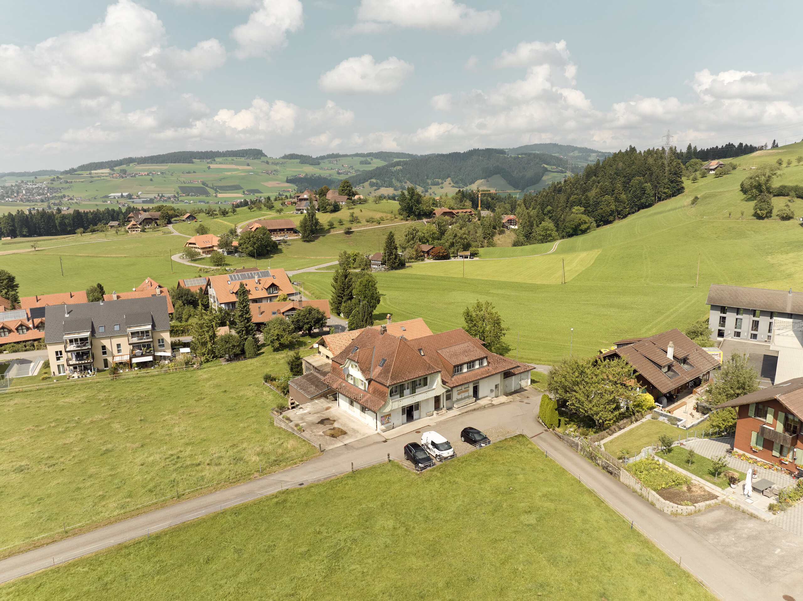 Luftaufnahme einer ländlichen Hügellandschaft mit verstreuten Häusern