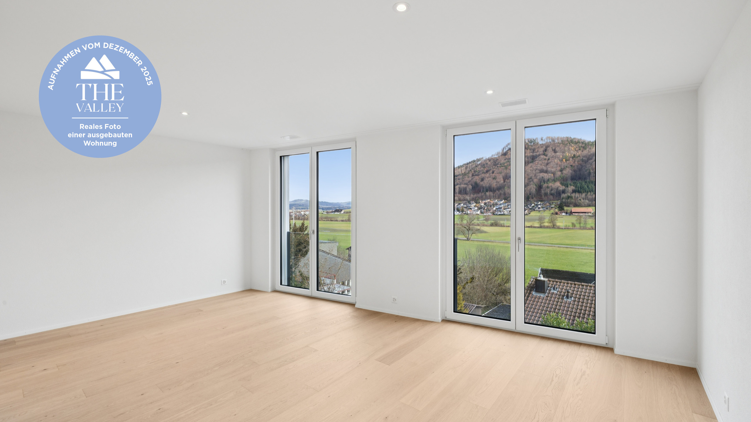 Heller leerer Wohnraum mit Panoramafenstern und Talblick