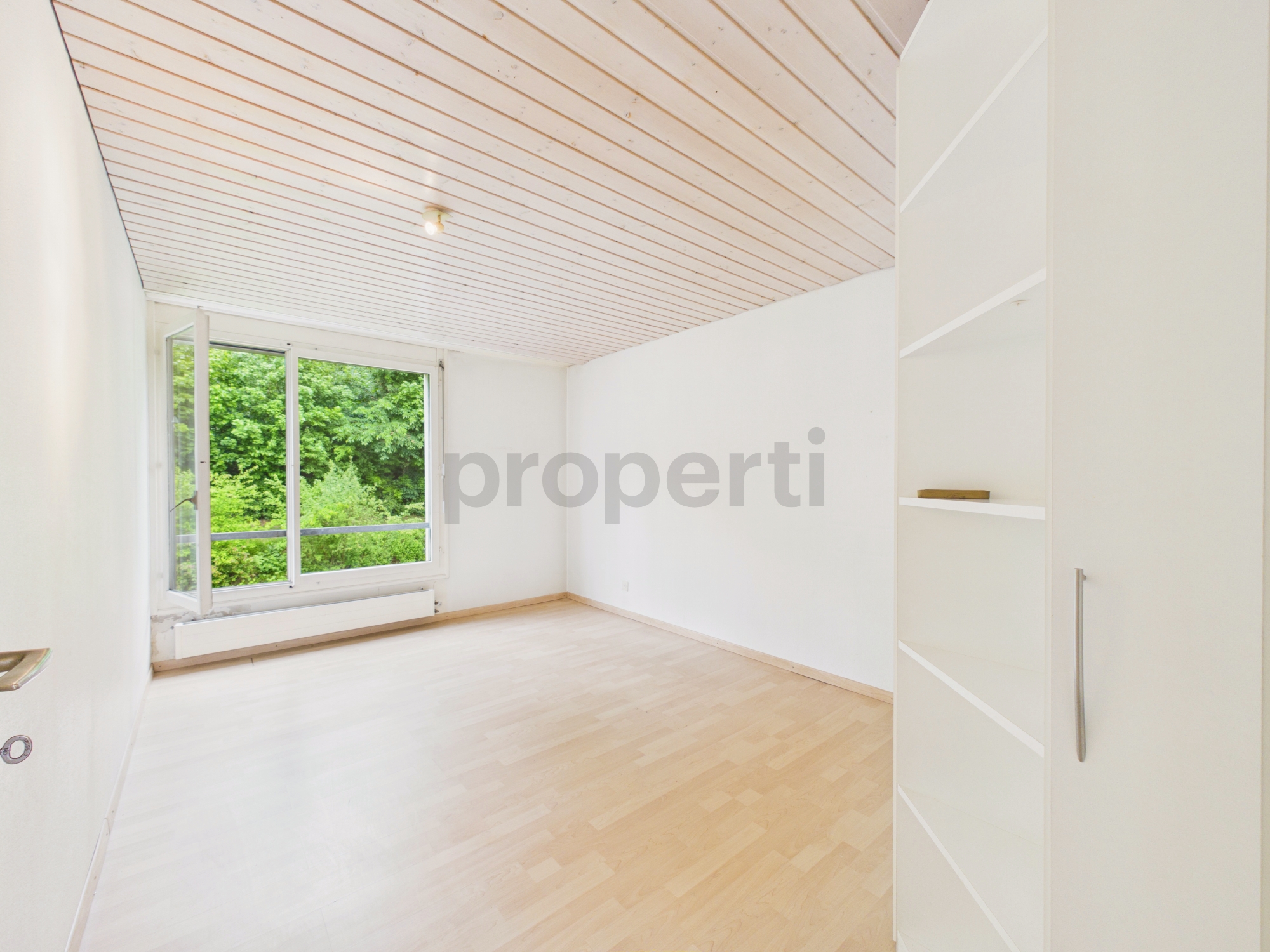 Helles, leeres Zimmer mit großem Fenster