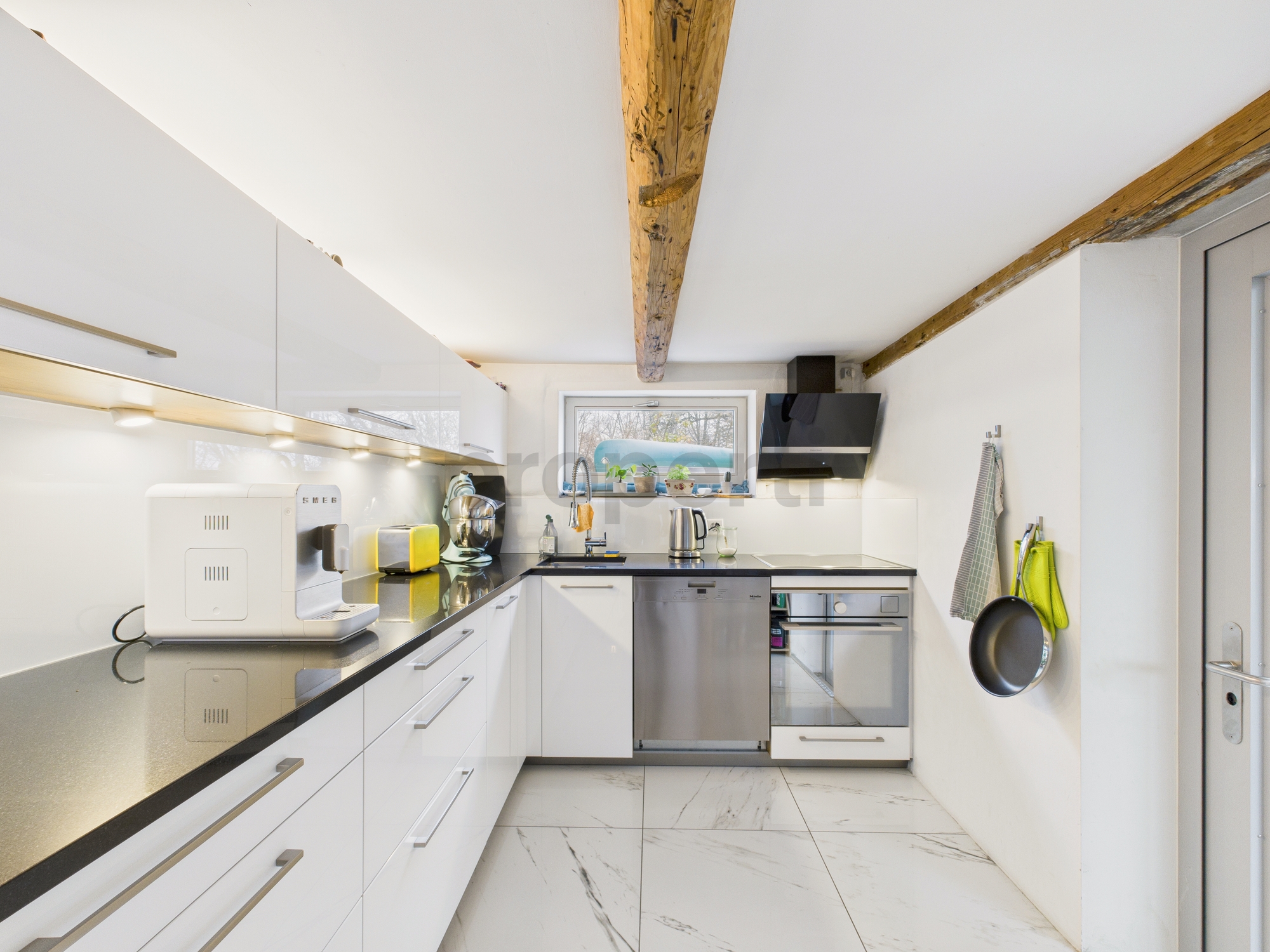 Moderne Dachgeschossküche mit sichtbaren Holzbalken