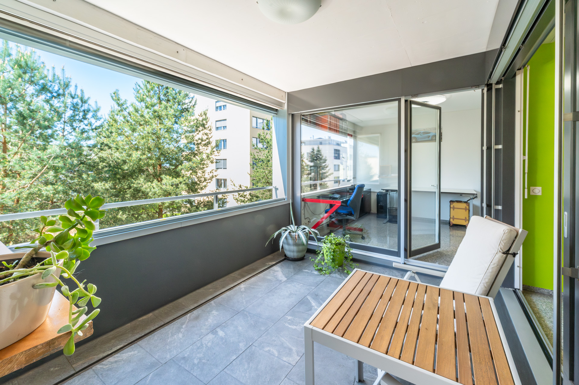 Überdachter Balkon mit Arbeitsplatz und Blick ins Grüne
