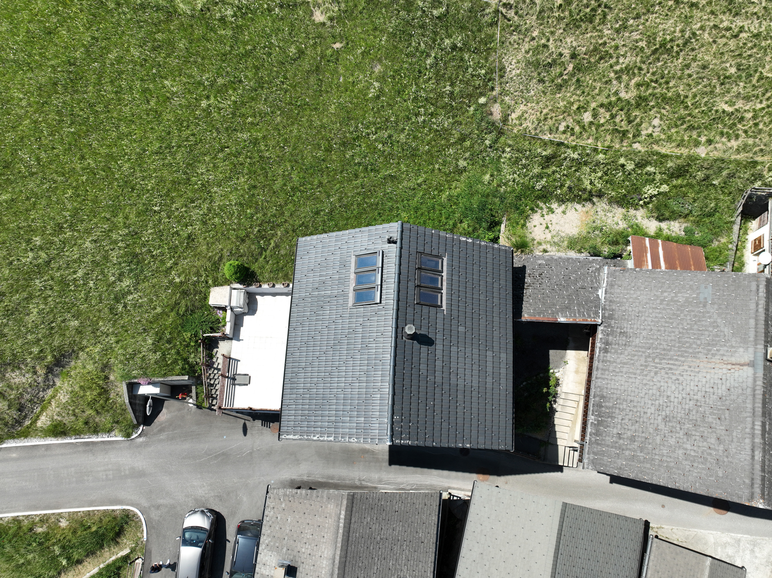 Luftaufnahme eines Hauses mit angrenzenden Dachflächen und Wiesen
