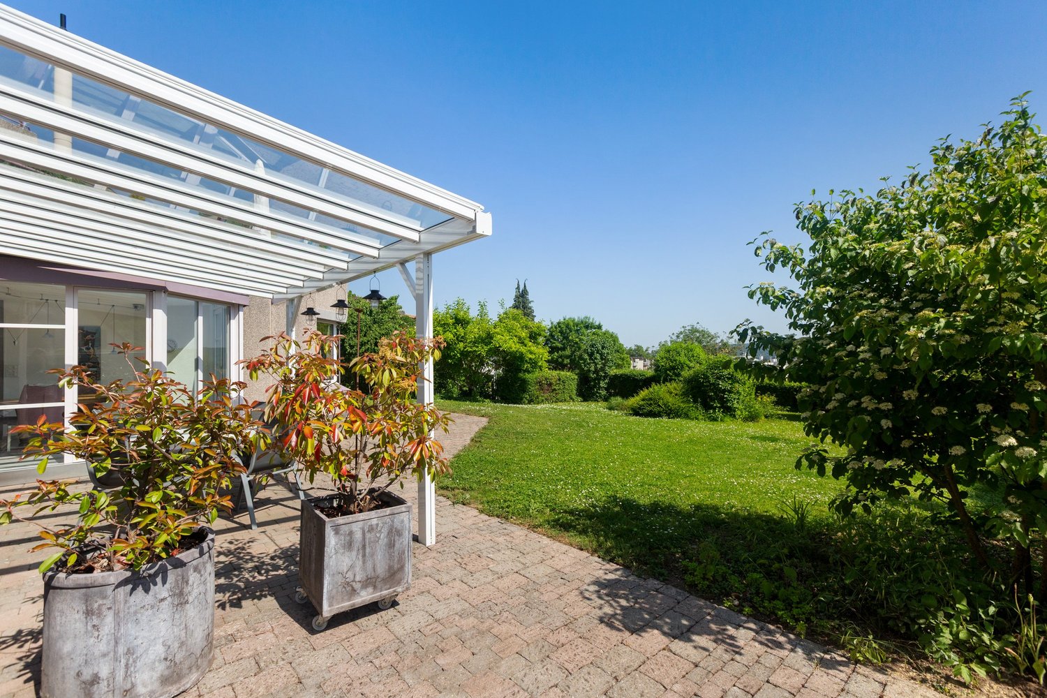 Terrasse mit Glasüberdachung und Gartenblick