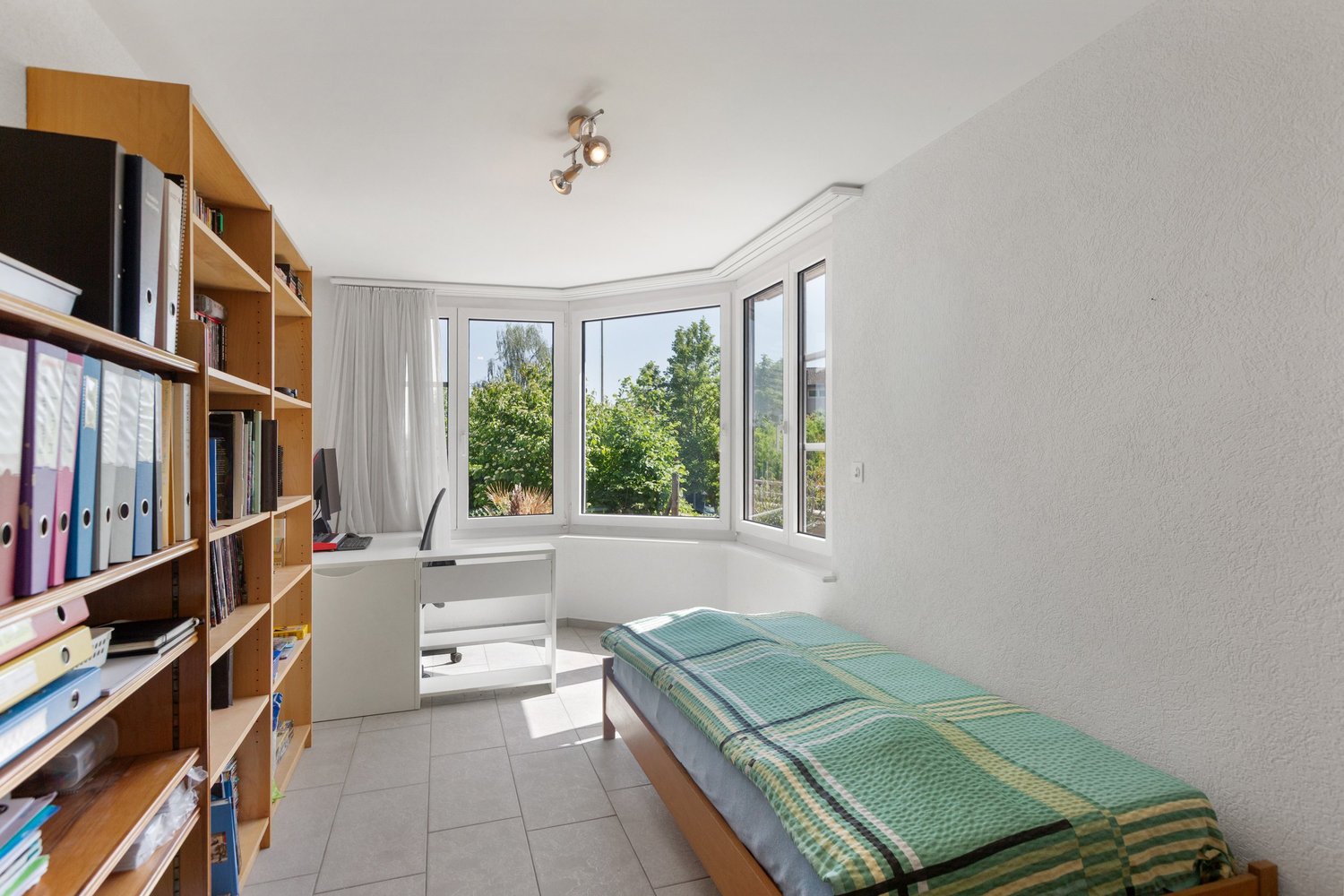 Helles Zimmer mit Bett, Schreibtisch und Fensterfront
