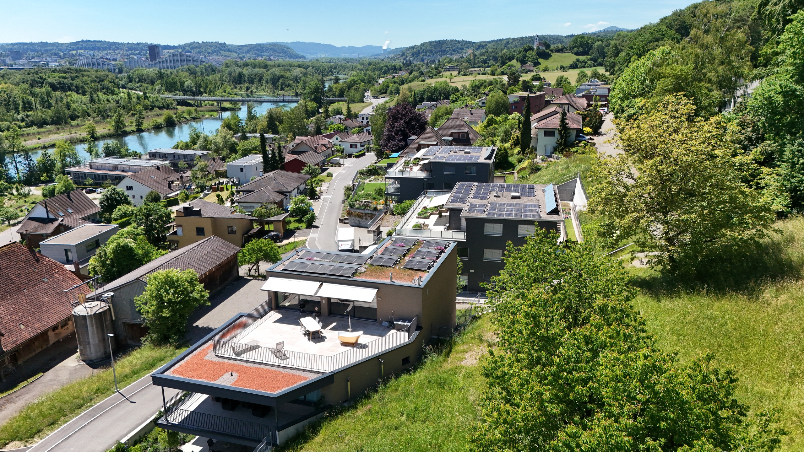 Luftaufnahme eines Wohngebiets mit Flussblick und begrünten Hängen