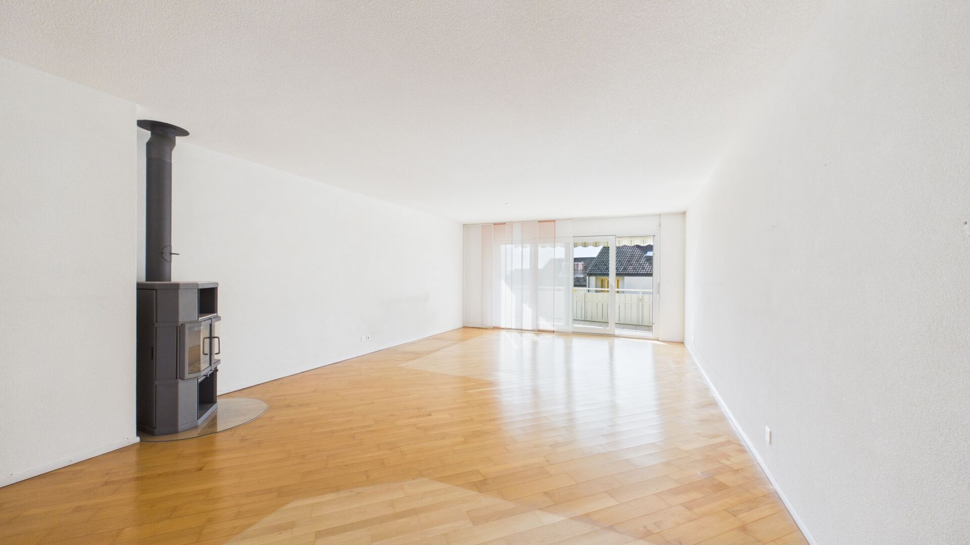 Heller Wohnraum mit Kaminofen und Balkonblick