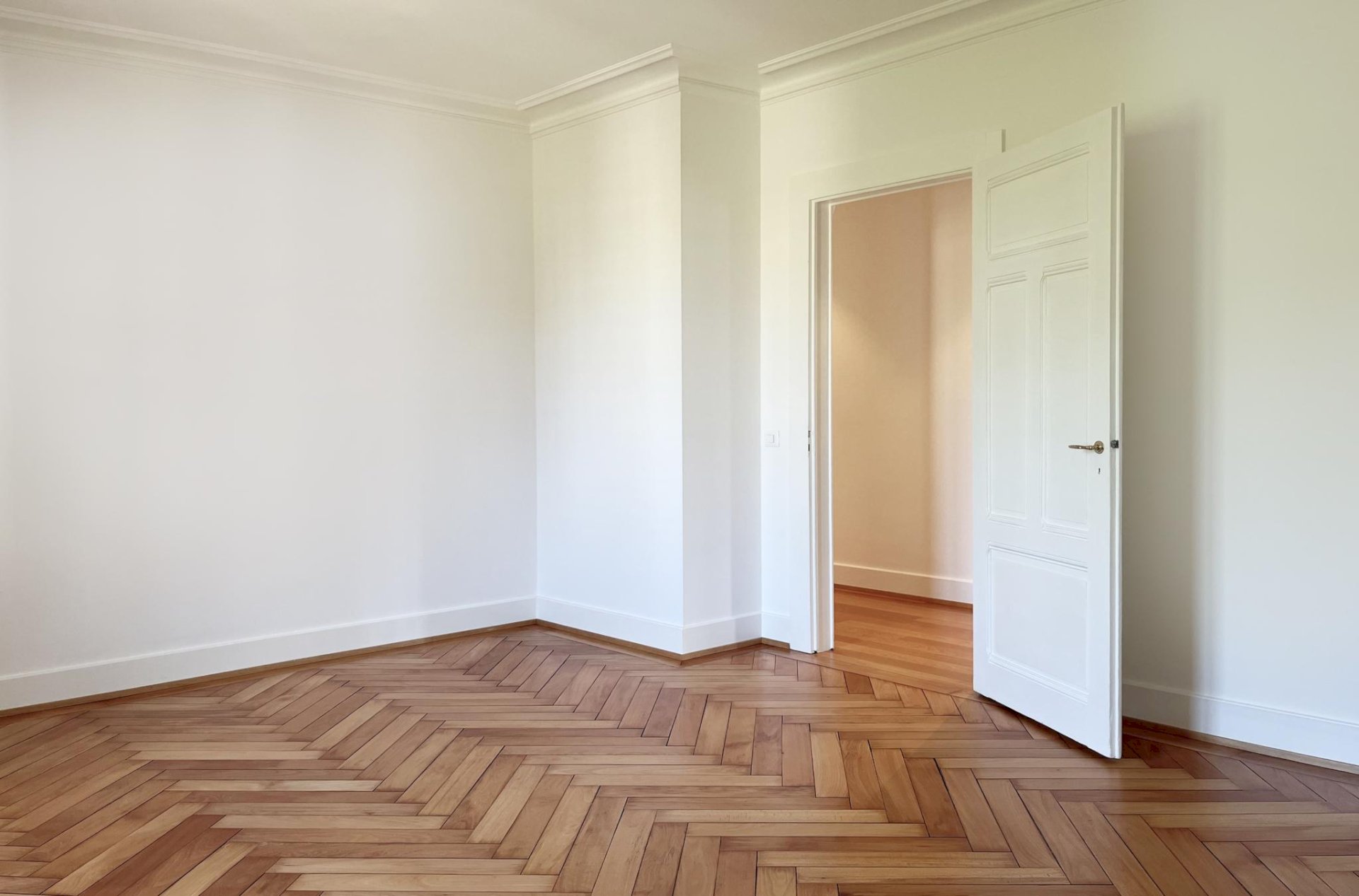 Heller leerer Altbau-Raum mit Fischgrätparkett und Flügeltür
