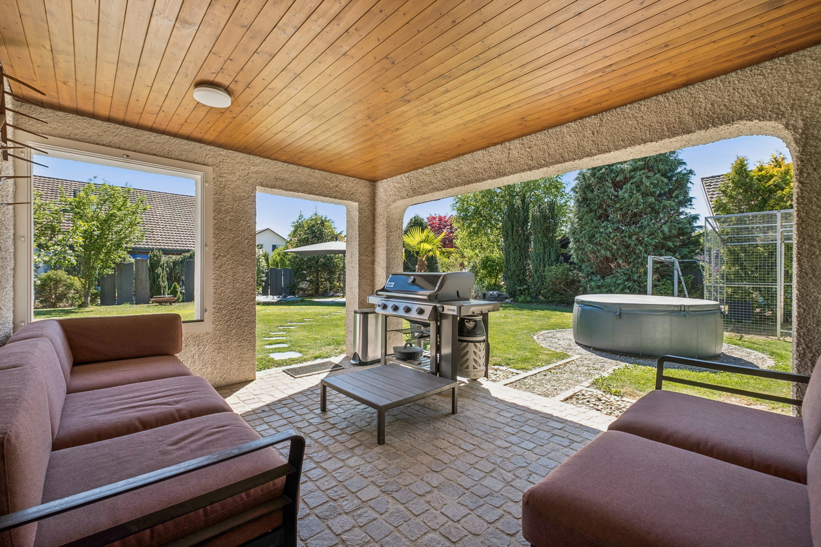 Überdachte Gartenlounge mit Grill und Whirlpool