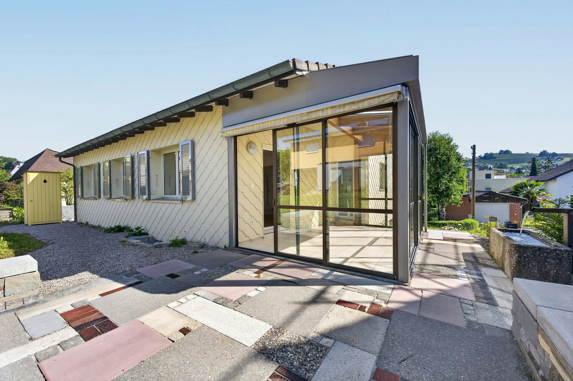 Außenansicht eines eingeschossigen Hauses mit Wintergarten