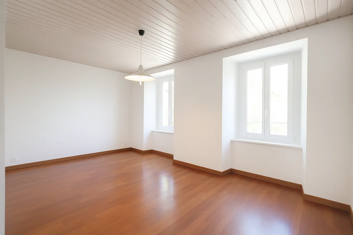 Heller leerer Wohnraum mit Holzfußboden und zwei Fenstern