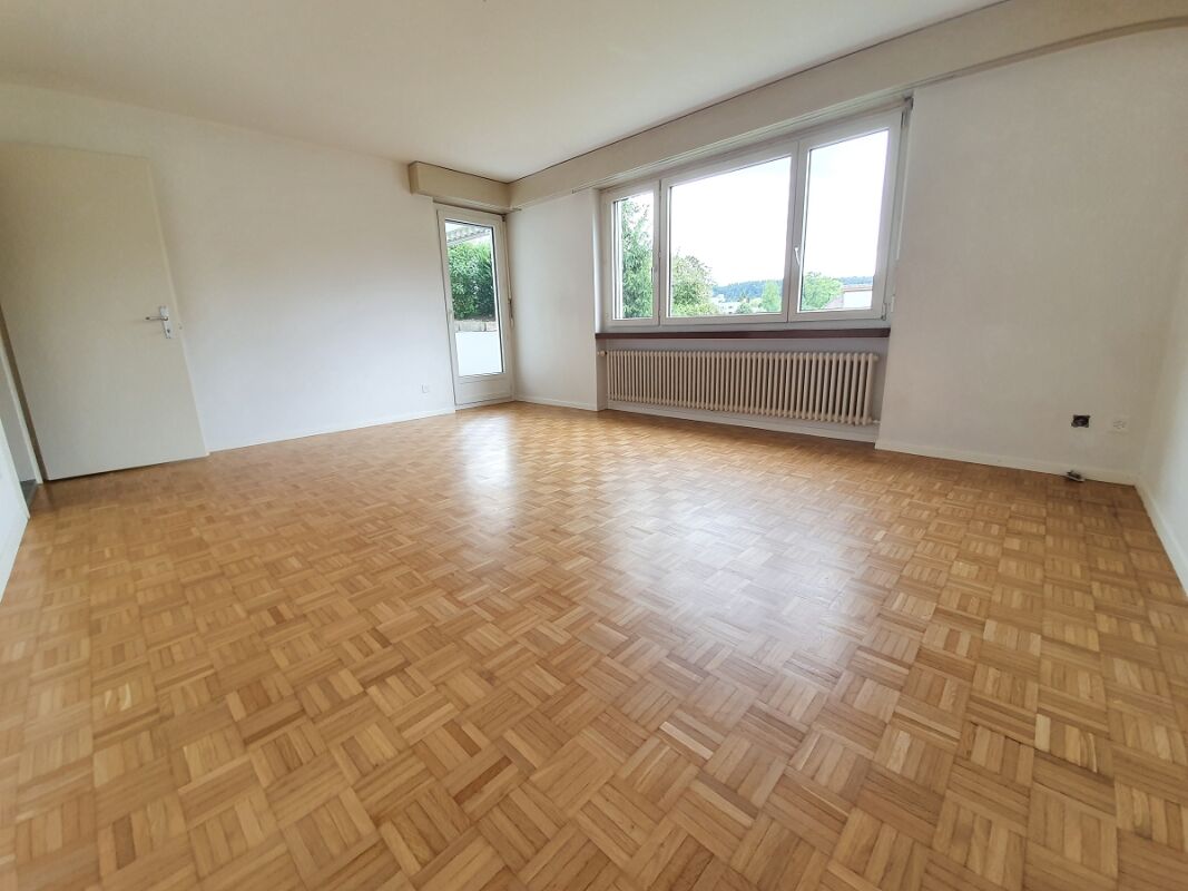 Leerer Wohnraum mit Parkettboden und großem Fenster
