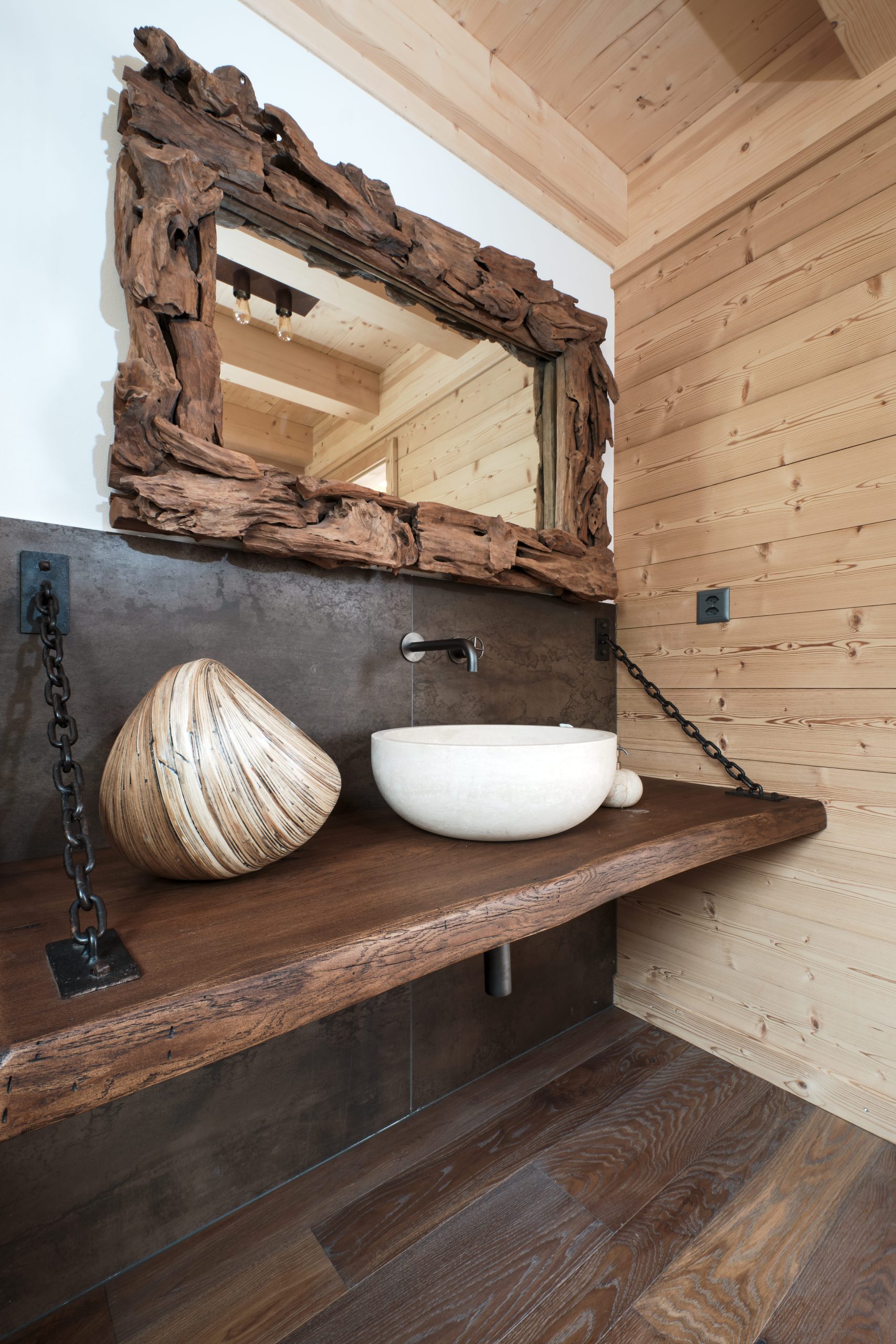 Rustikales Badezimmerdetail mit Naturholz und Baumstammspiegel
