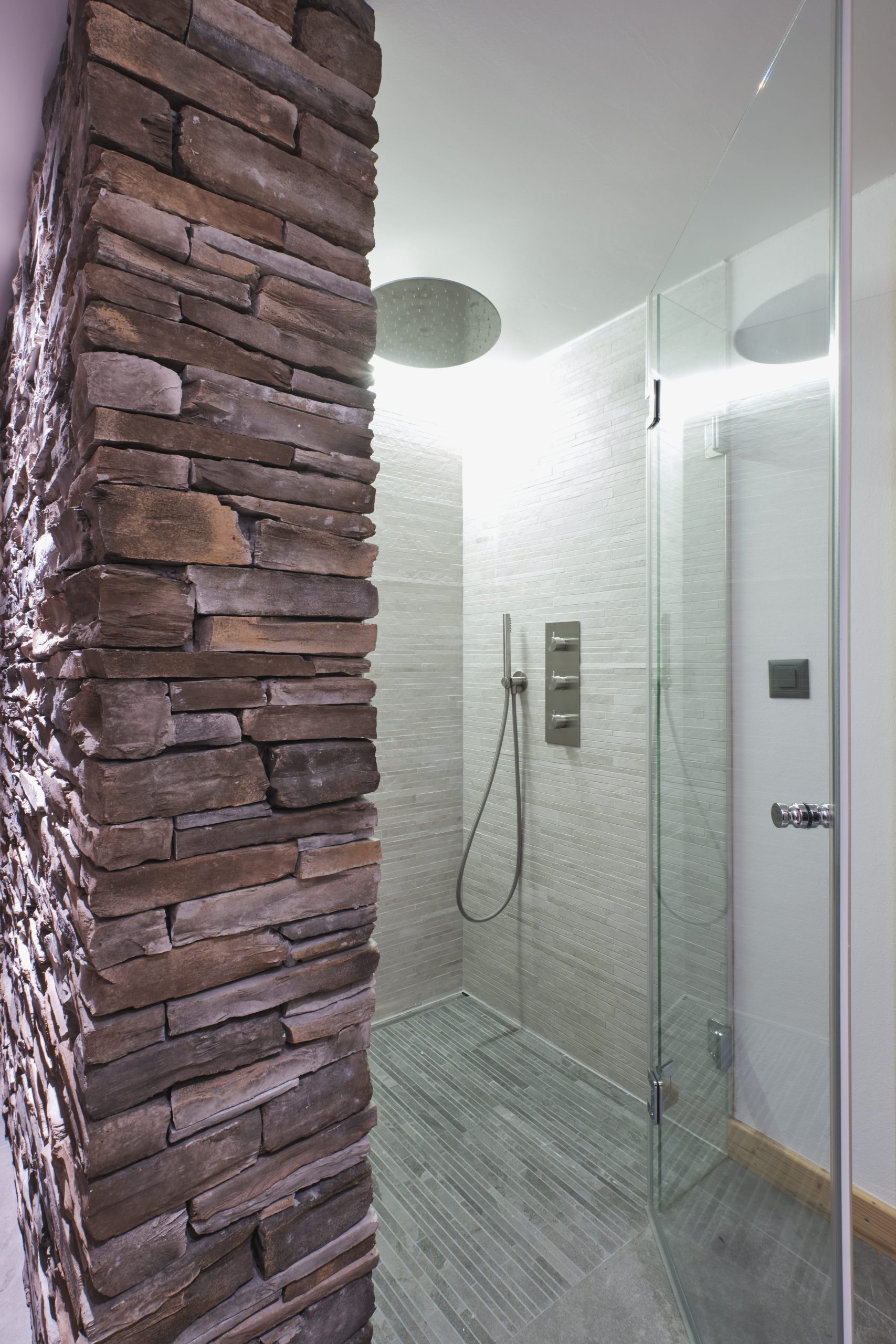 Moderne begehbare Dusche mit Steinwand