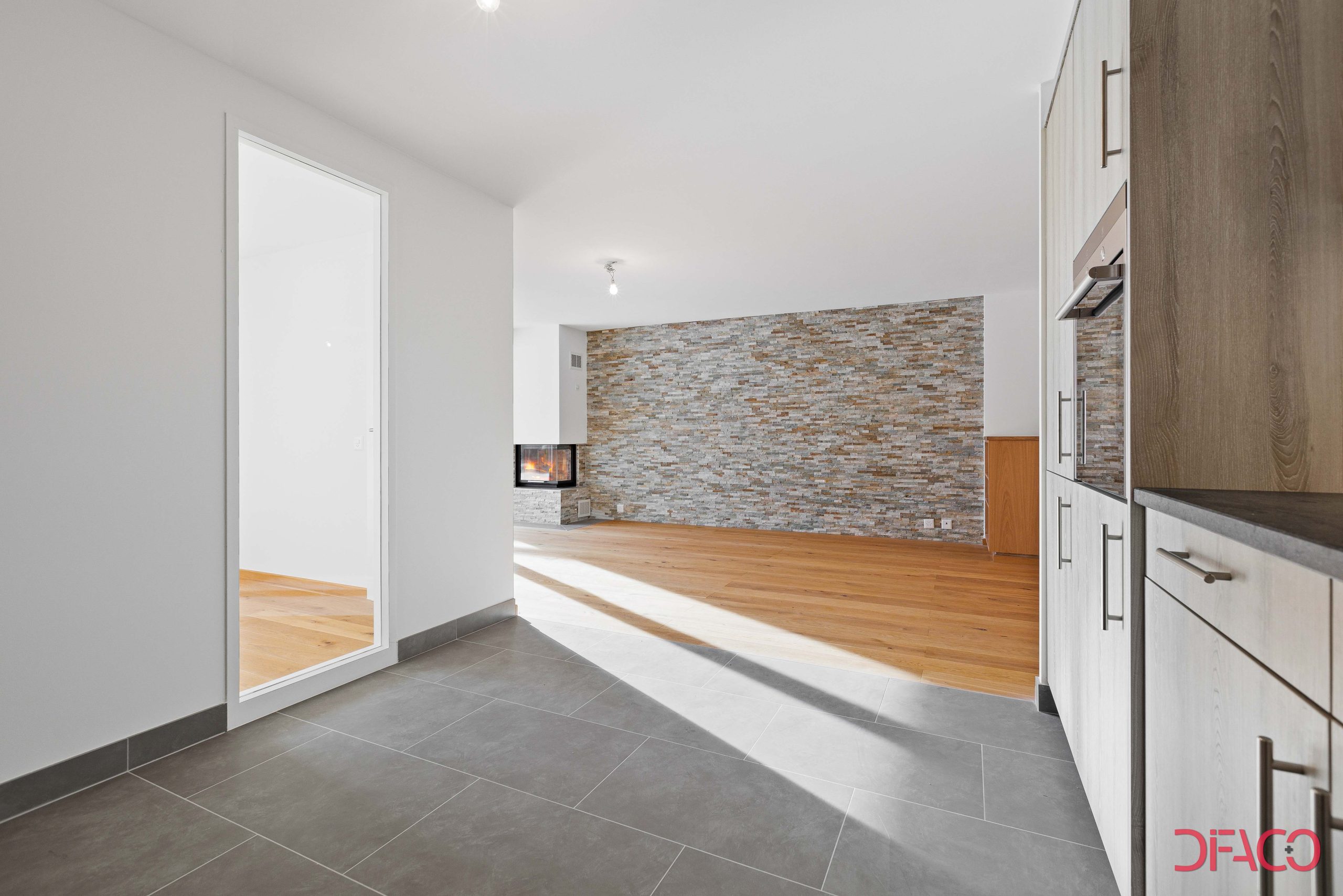 Heller, moderner Wohnbereich mit Kamin und Natursteinwand