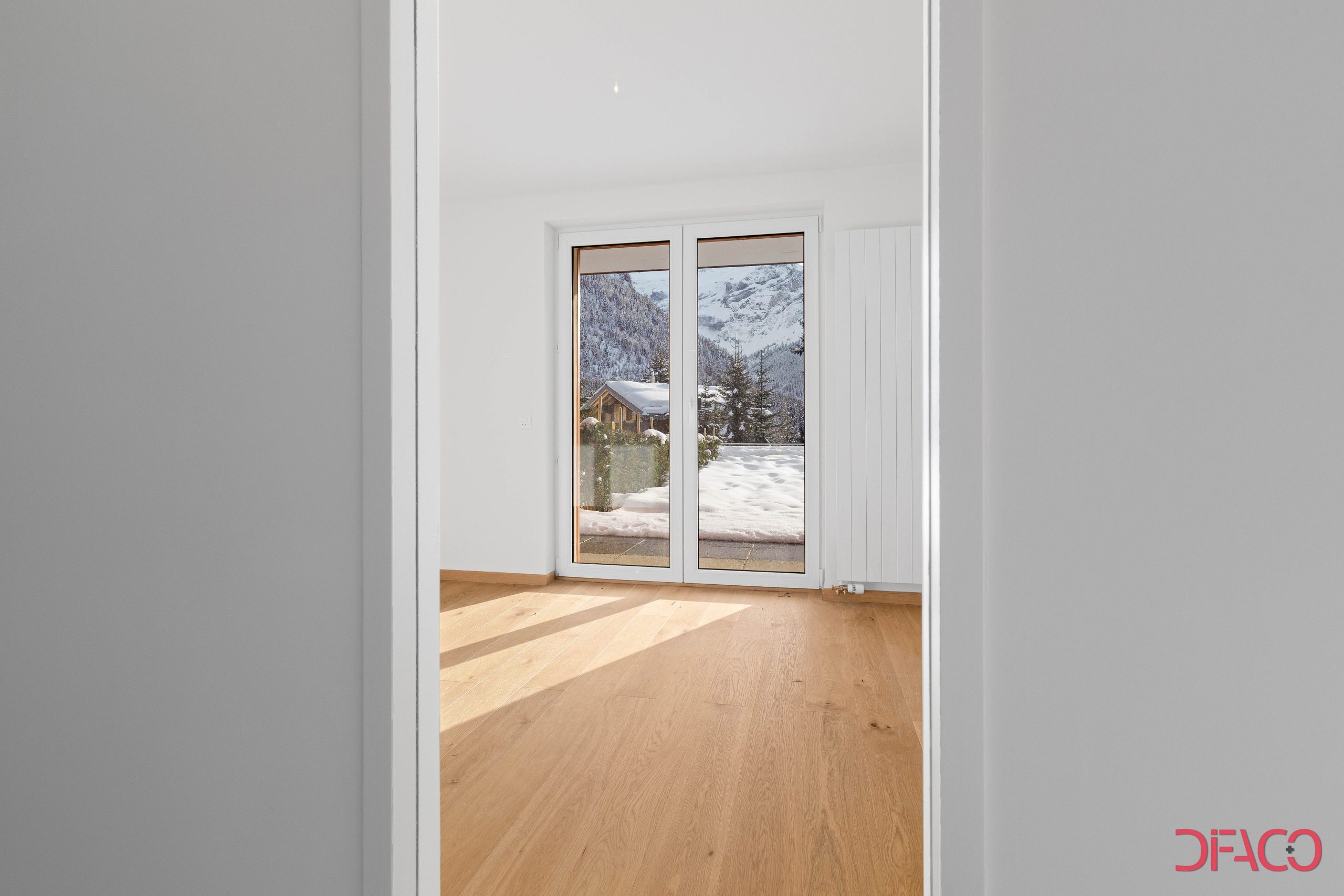 Heller Raum mit bodentiefen Fenstertüren und Bergblick