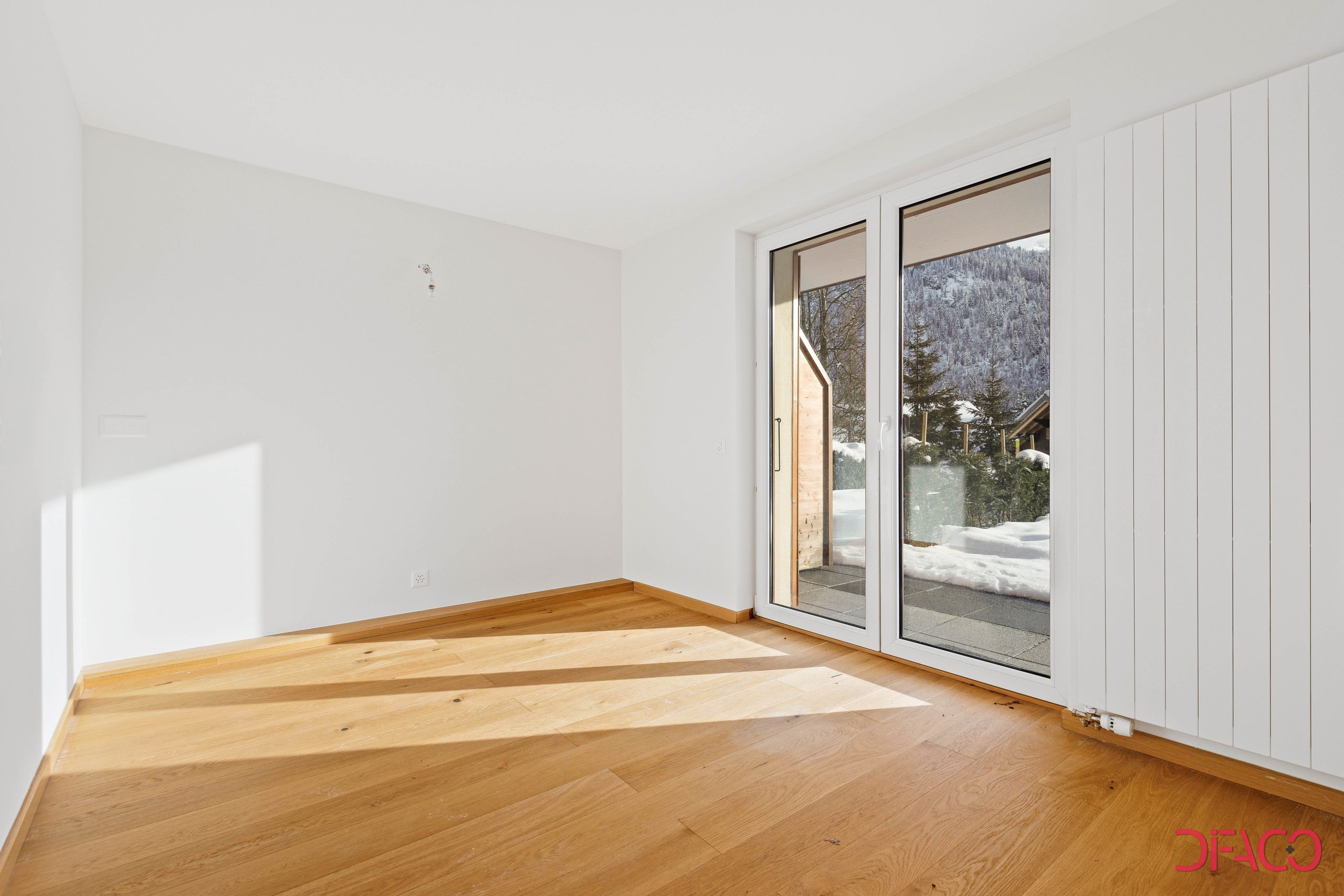 Helles, leeres Zimmer mit Balkon-/Terrassentür und Bergblick