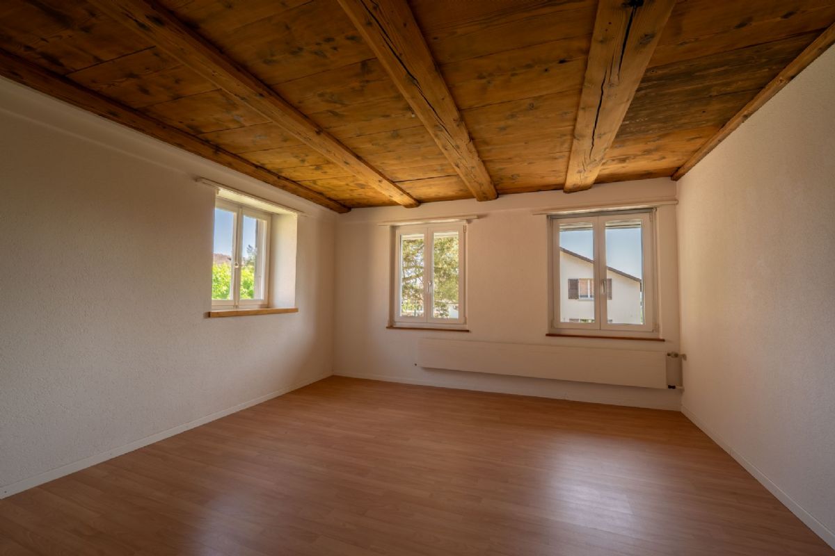 Leerer Raum mit Holzdecke und drei Fenstern