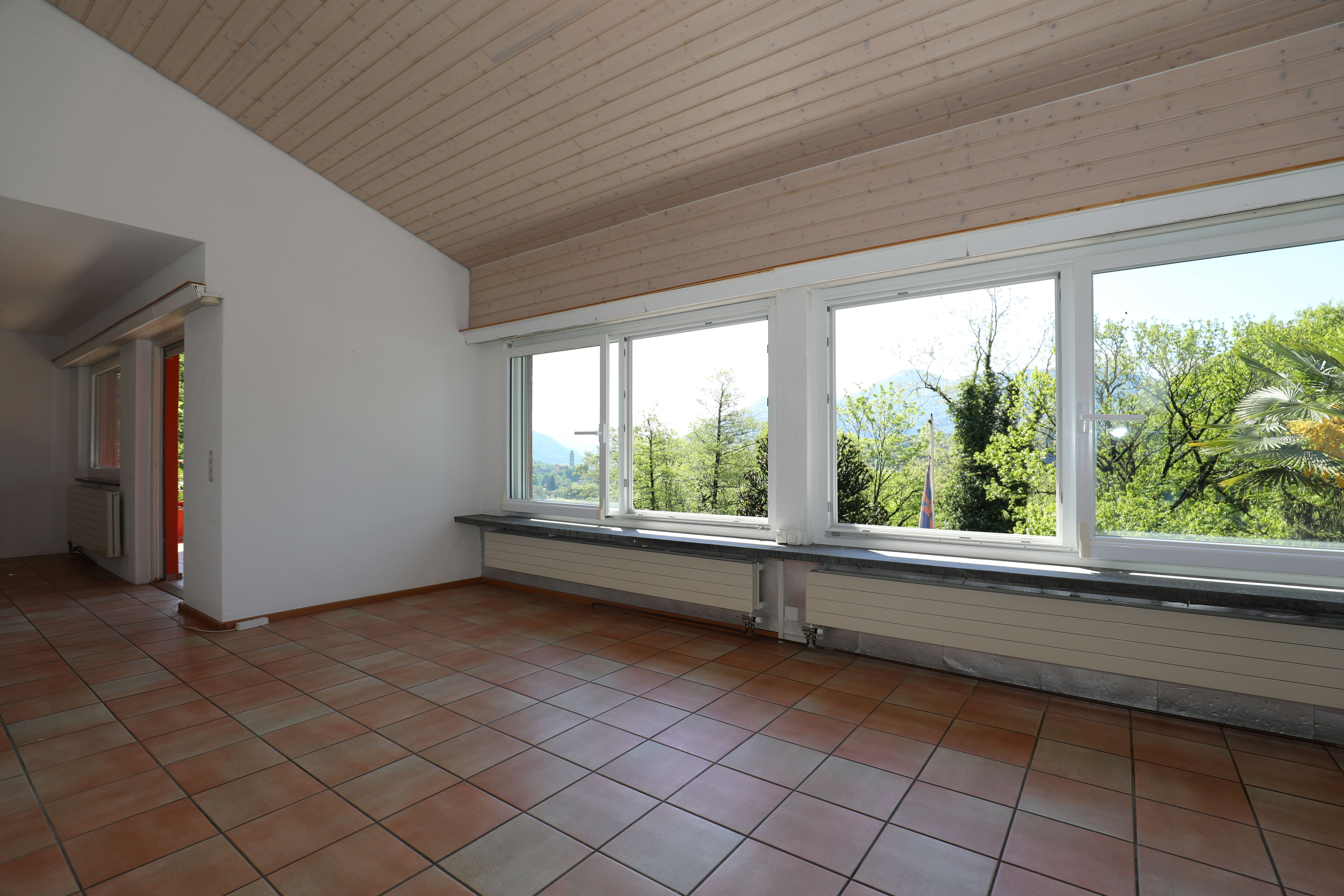 Heller Innenraum mit großem Fensterband und Terrakottafliesen
