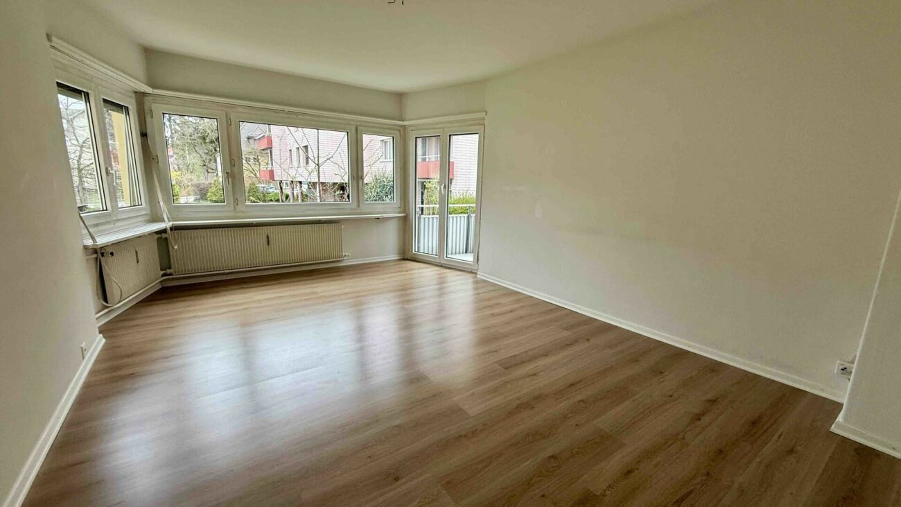 Helles Wohnzimmer mit großen Fenstern und Balkonzugang