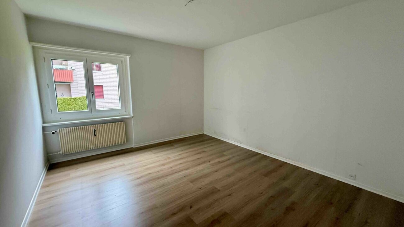 Leerer heller Wohnraum mit Fenster und Heizkörper