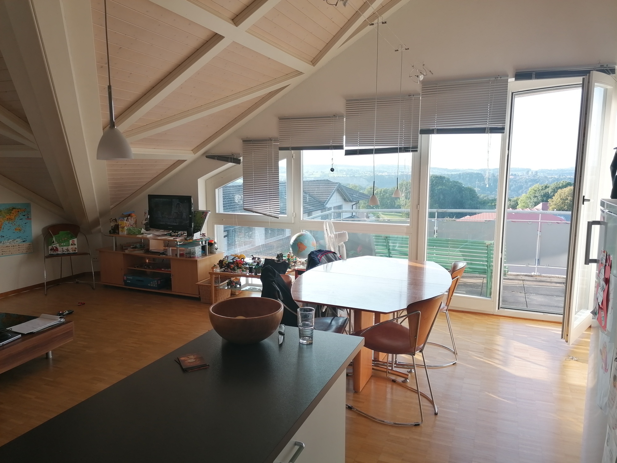 Helles Dachgeschoss-Wohnzimmer mit Essbereich und Balkonblick