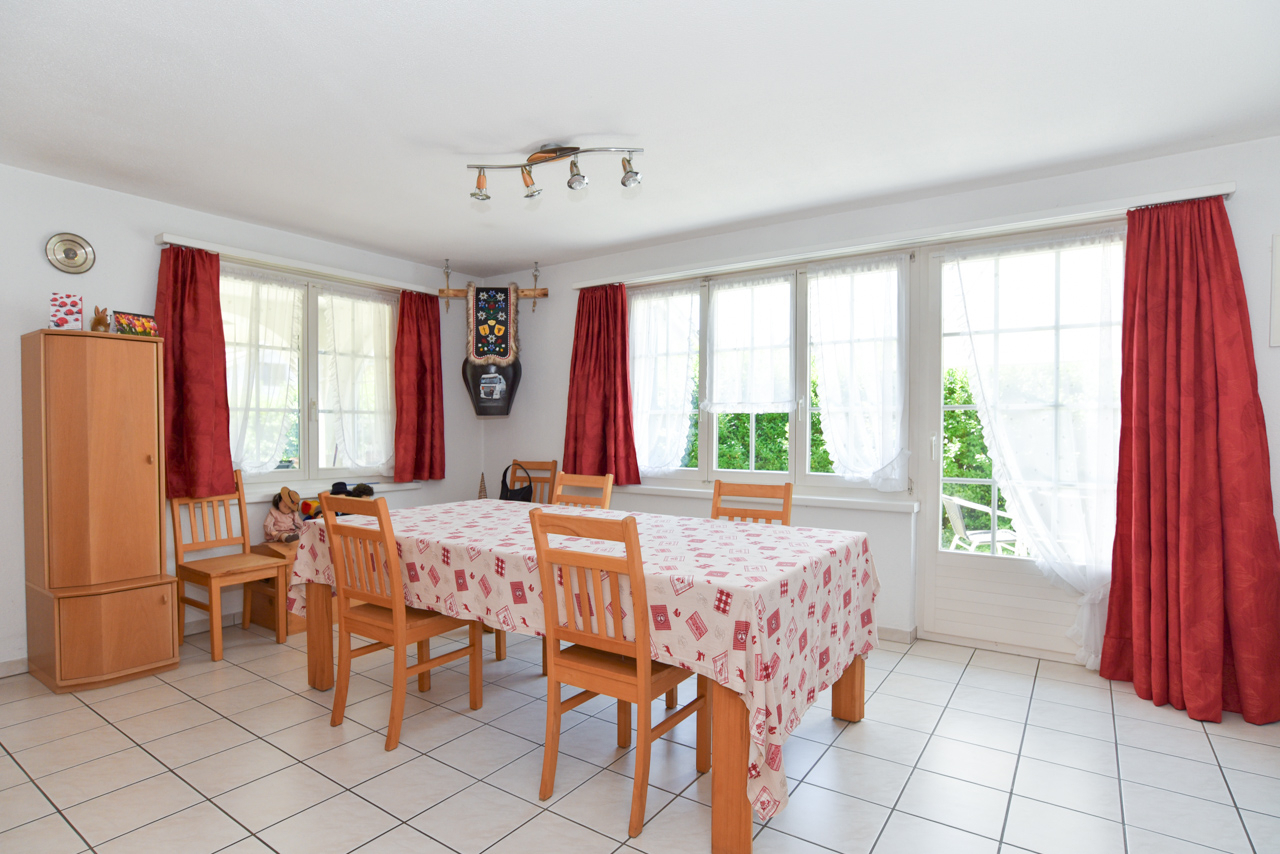 Helles Esszimmer mit großen Fenstern und rotem Vorhang