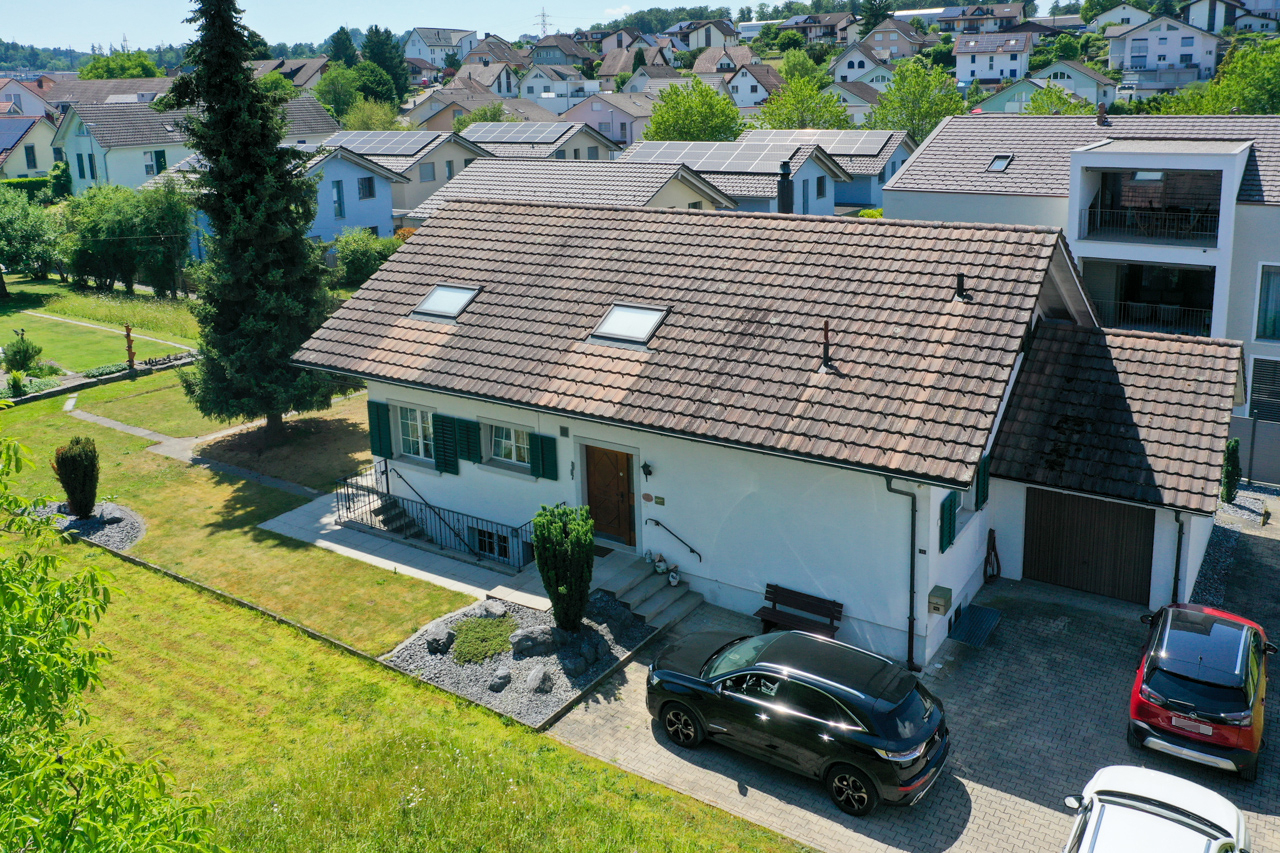 Außenansicht eines Einfamilienhauses mit Garten und Garage