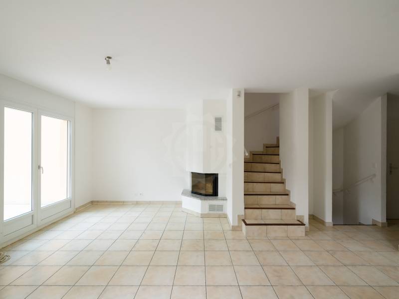 Heller leerer Wohnbereich mit Kamin und Treppe