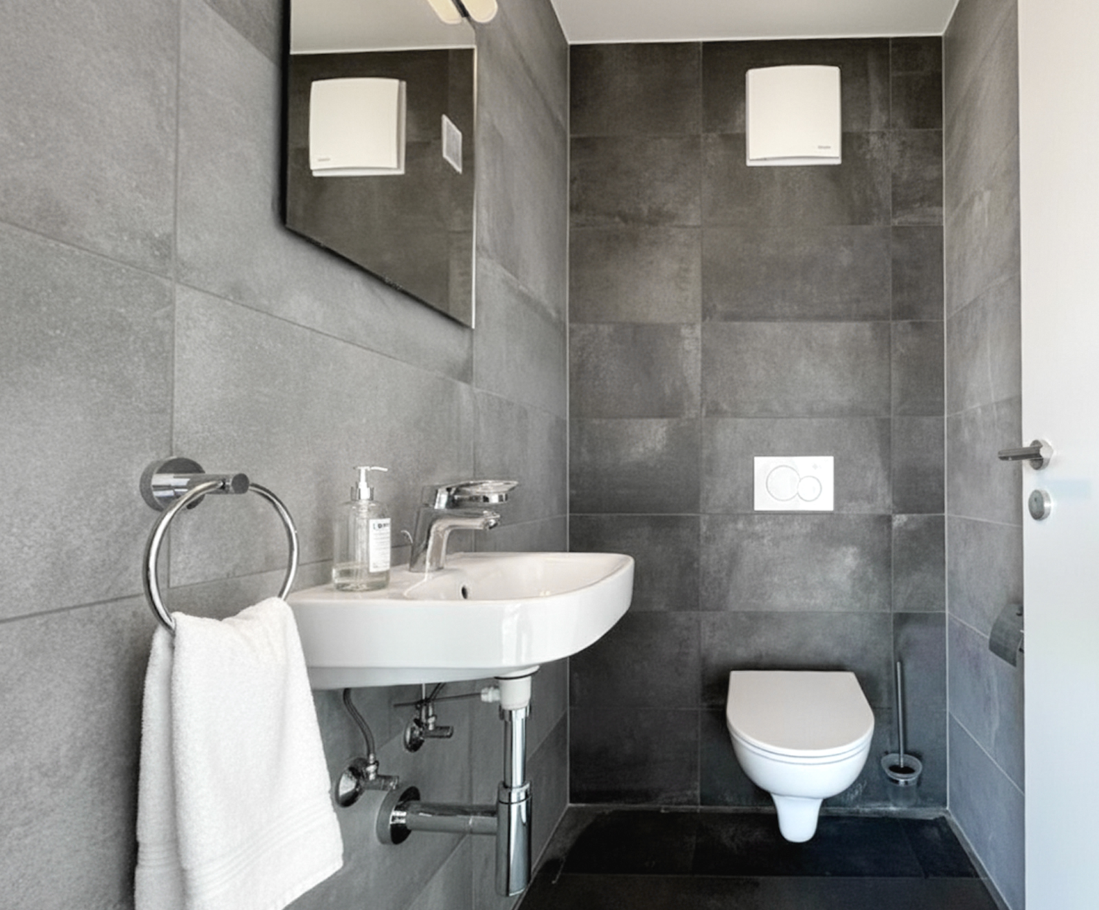 Modernes Gäste-WC mit grauen Fliesen und wandhängendem WC
