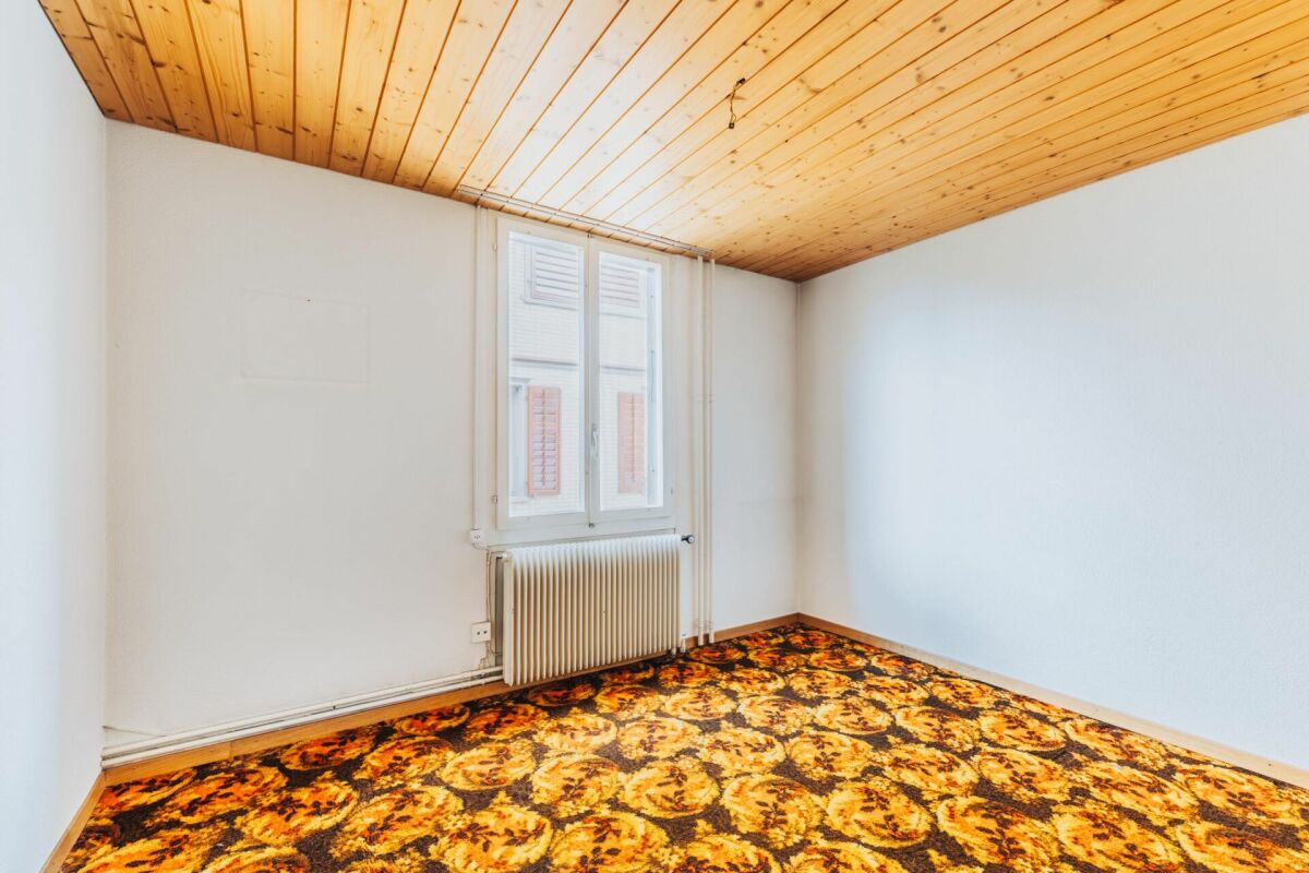 Leerer Raum mit Holzdecke und auffälligem Teppichboden