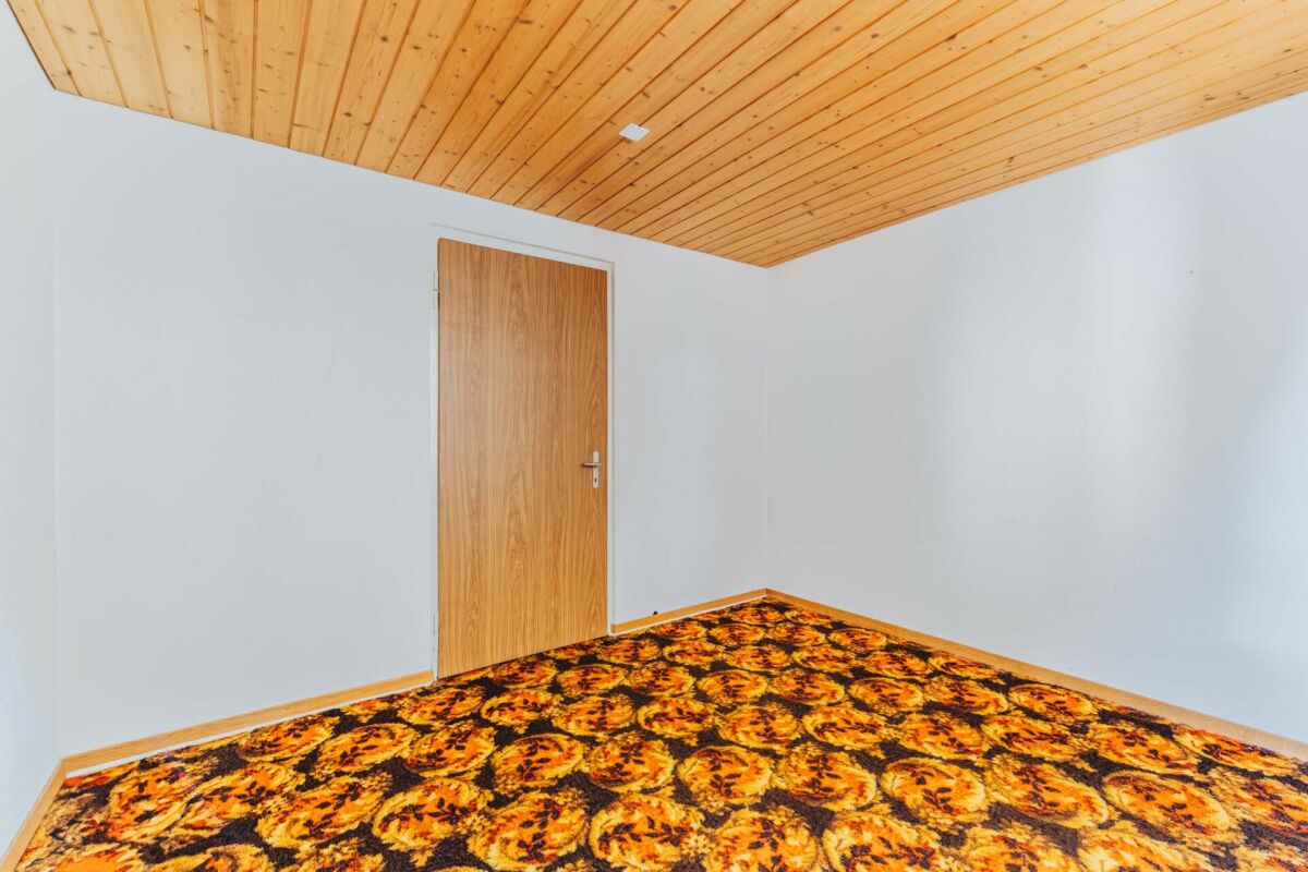 Leerer Innenraum mit Holztür und gemustertem Teppich