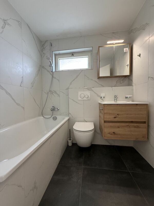 Modernes Bad mit Wanne und Holzwaschtisch