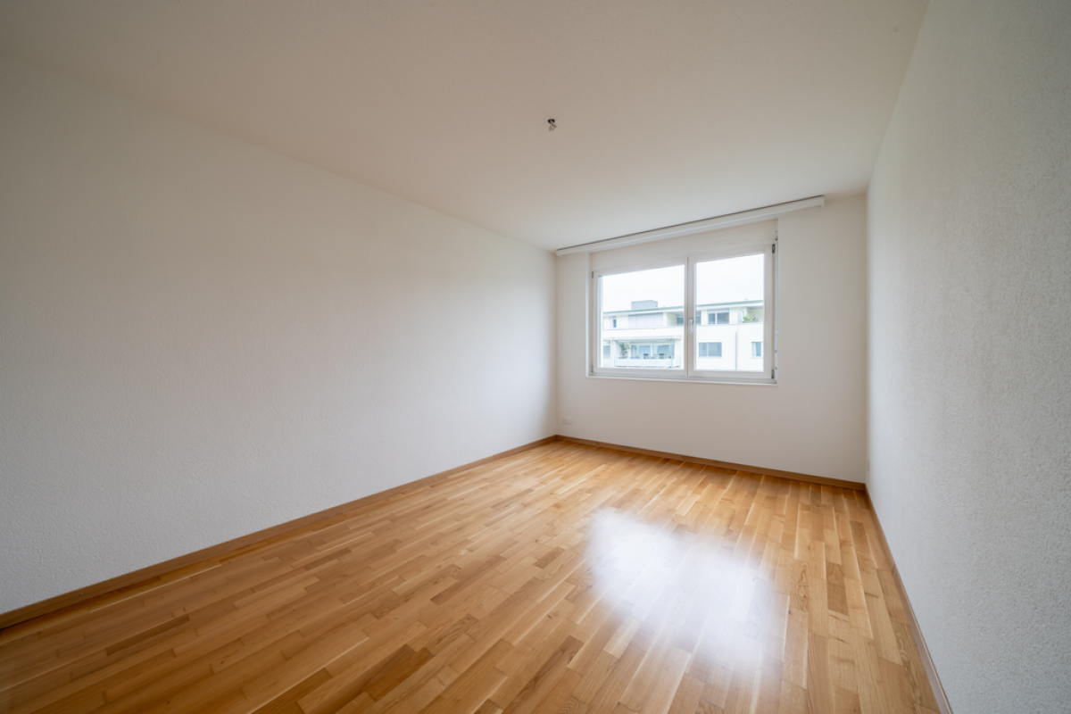 Leerer heller Wohnraum mit Parkett und Fenster