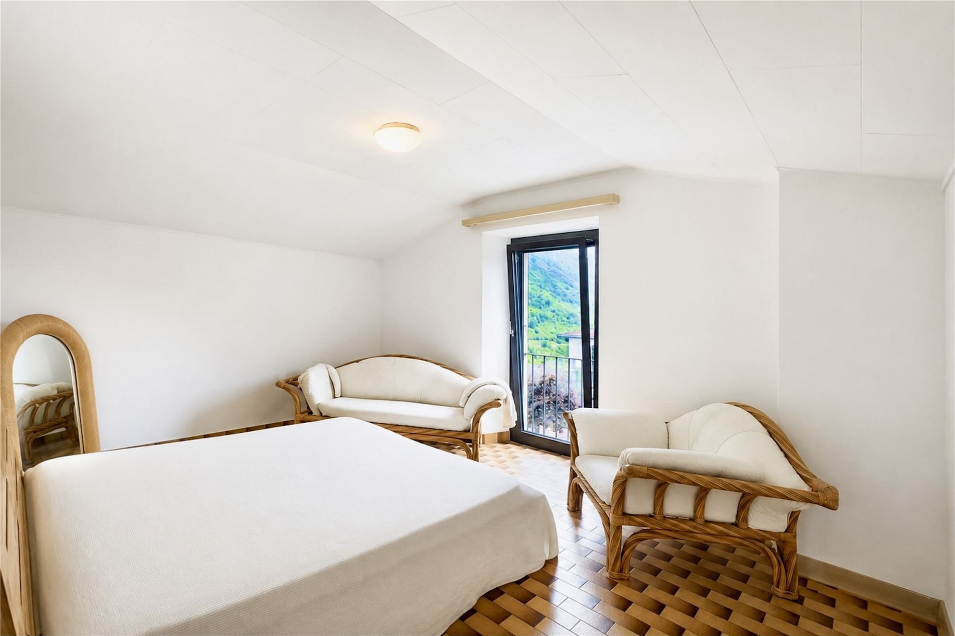 Schlafzimmer mit Rattanmöbeln und Balkonblick